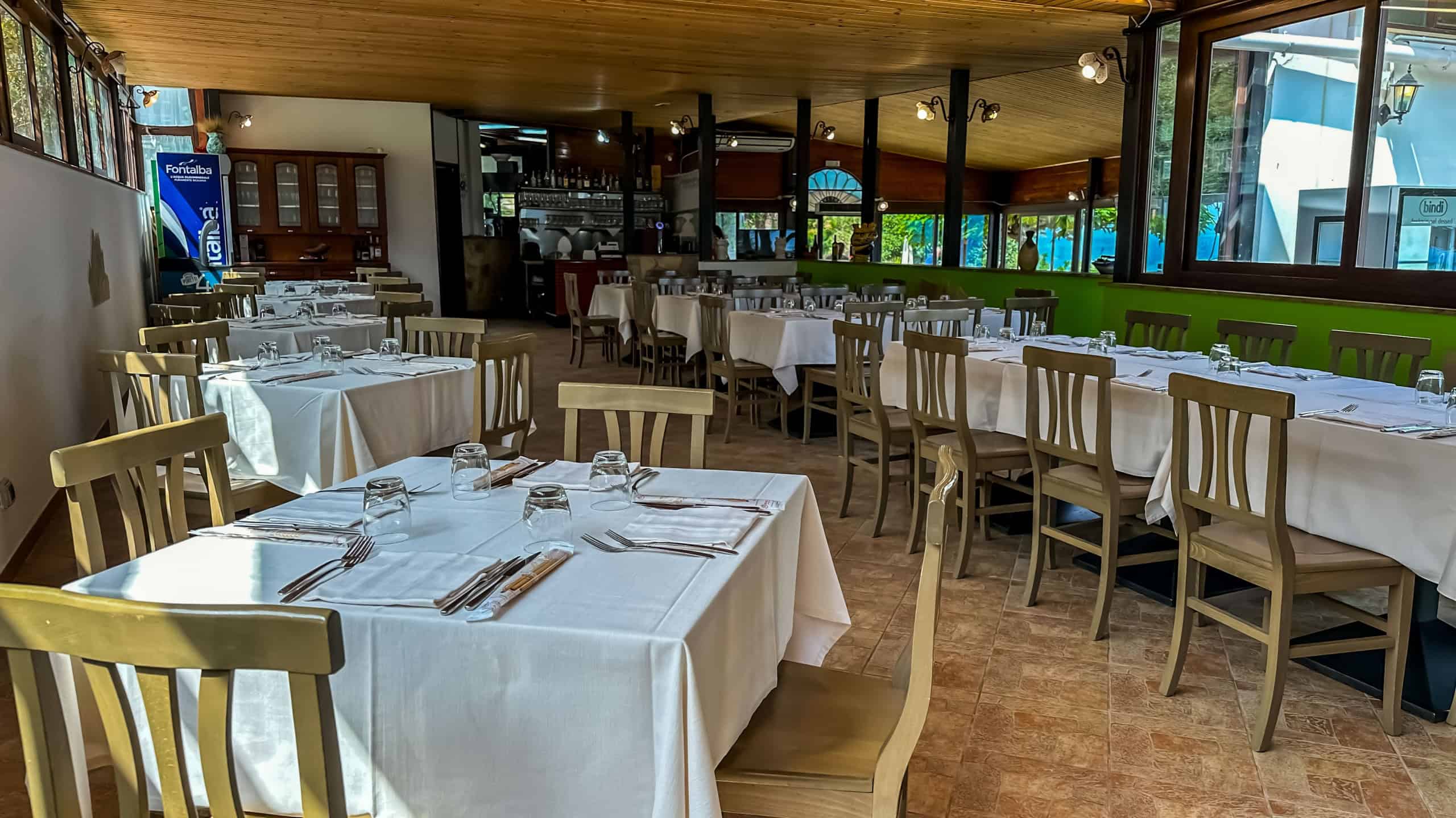 Elegante sala ristorante con tavoli imbanditi, atmosfera accogliente e arredi raffinati, ideale per pranzi e cene di qualità in un ambiente confortevole e ben arredato.
