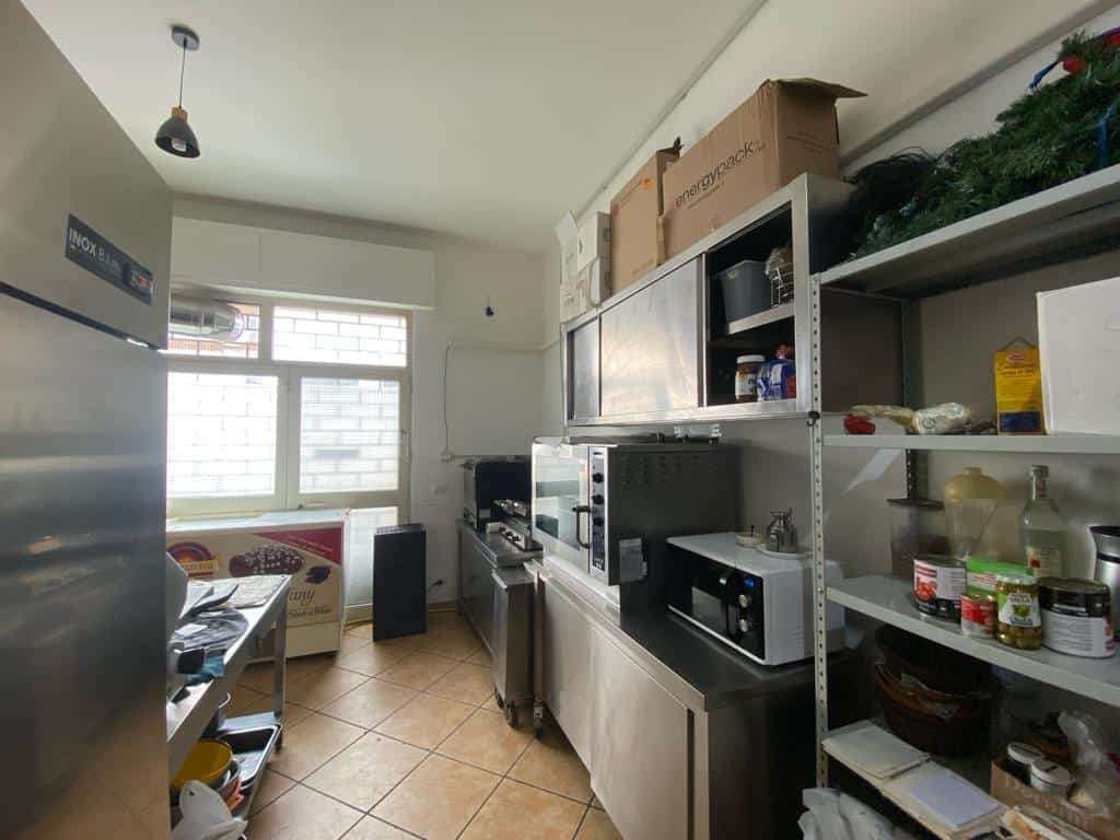Scaffale da cucina con vari alimenti e utensili, ambiente domestico ben organizzato, spazio funzionale per preparare i pasti, illuminazione naturale dalla finestra, atmosfera accogliente e pratica.