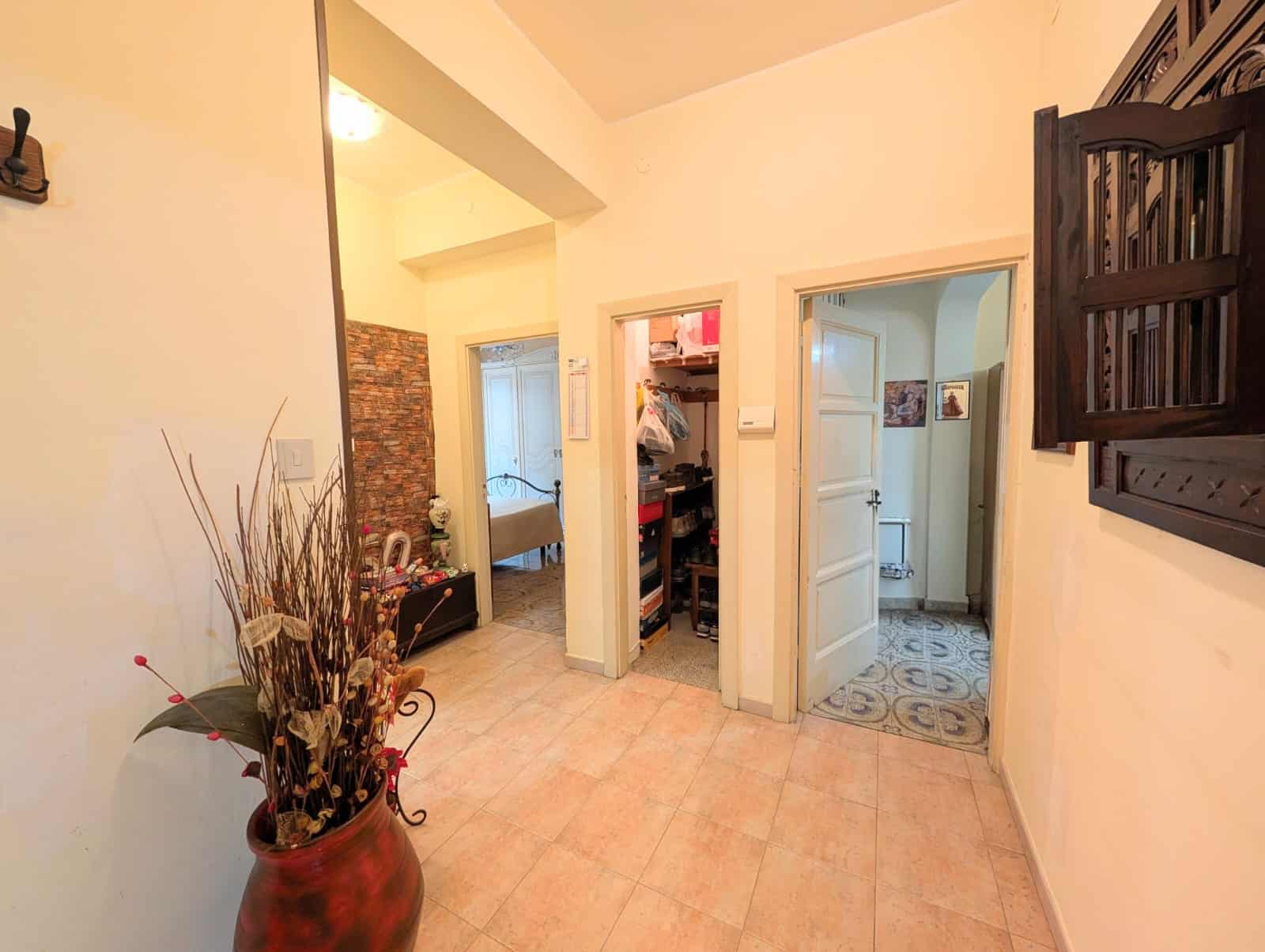 Ampio ingresso con arredi funzionali, pareti bianche e pavimento in piastrelle beige, ideale per accogliere gli ospiti e organizzare lo spazio di casa.