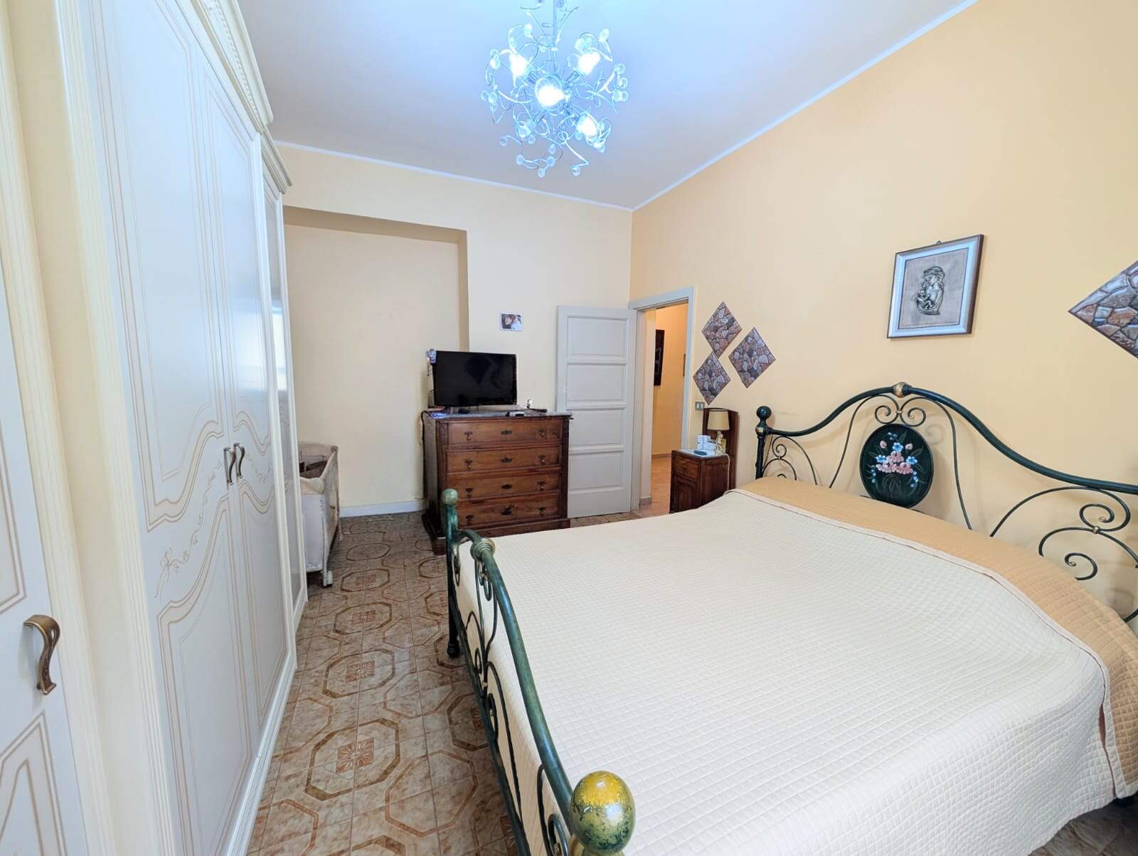 Letto matrimoniale in camera da letto con arredi classici, pareti color crema e decorazioni eleganti, ambiente accogliente e luminoso.