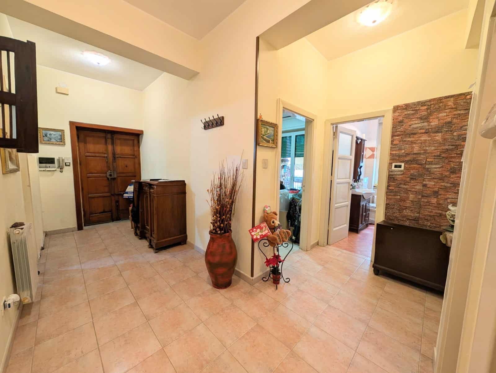 Ingresso di casa con arredi eleganti e decorazioni accoglienti, pavimento in piastrelle e pareti chiare, porta d'ingresso in legno e accessori di design, ambiente luminoso e spazioso.