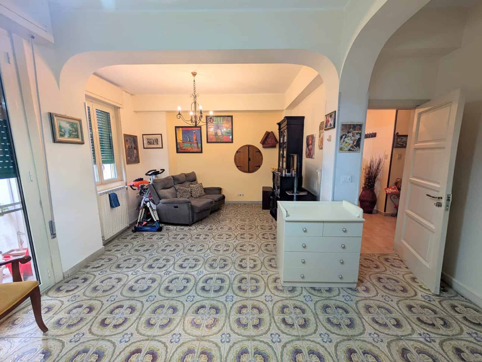 Ampio soggiorno con divano, biciclette e decorazioni artistiche, luminoso e accogliente, ideale per vivere momenti di relax e convivialità in casa.