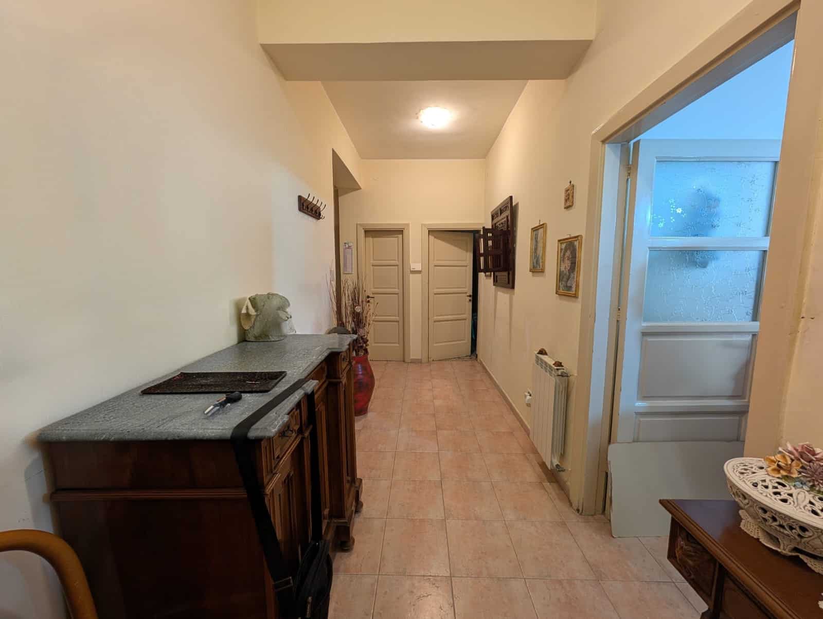 Aria di ingresso luminosa con mobili classici, pareti decorate e accessori eleganti, ideale per creare un'atmosfera accogliente e raffinata in casa.