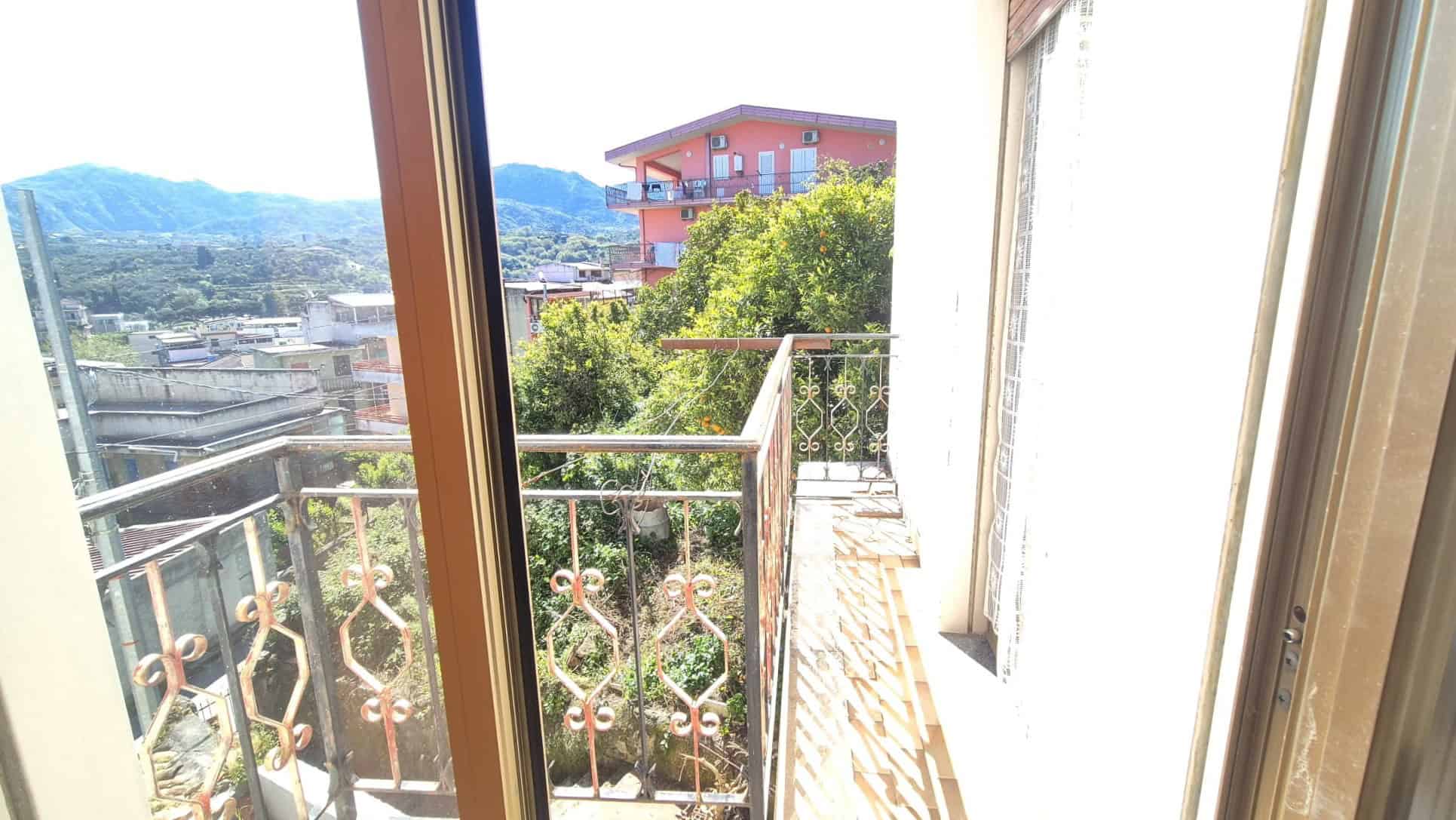 Balcone con vista panoramica su città e montagne, con ringhiera in ferro battuto e ambiente luminoso, ideale per relax e momenti all'aperto.
