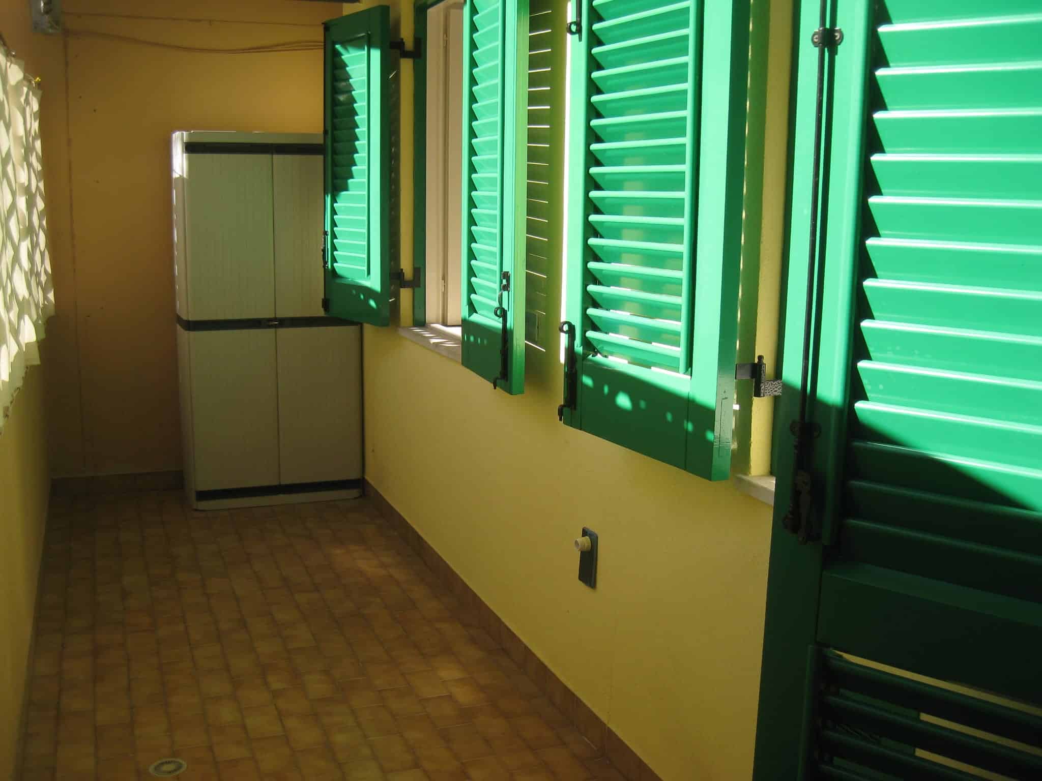 Vetrate con persiane verdi in una stanza luminosa e accogliente, ideale per ambienti residenziali o uffici, con luce naturale che crea un'atmosfera fresca e rilassante.