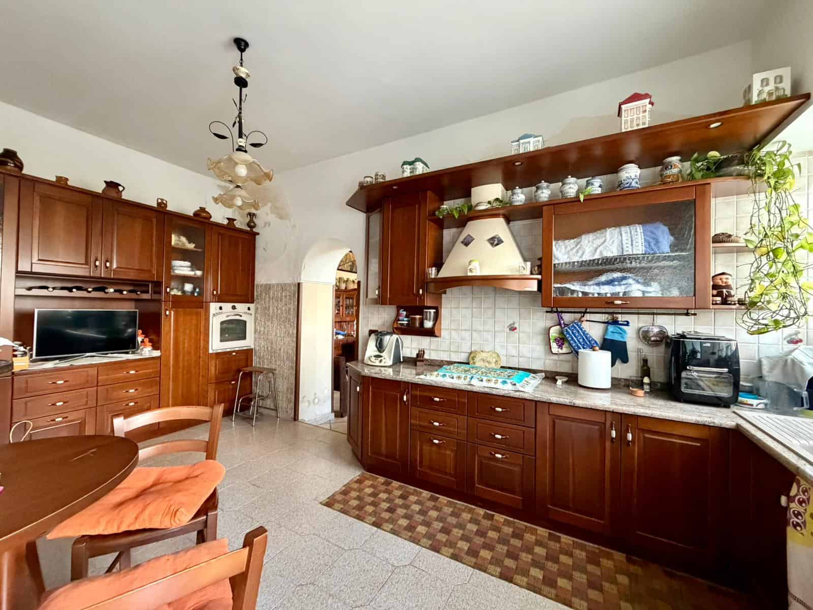 Cucina classica in legno con elettrodomestici e decorazioni, ambiente accogliente e luminoso.