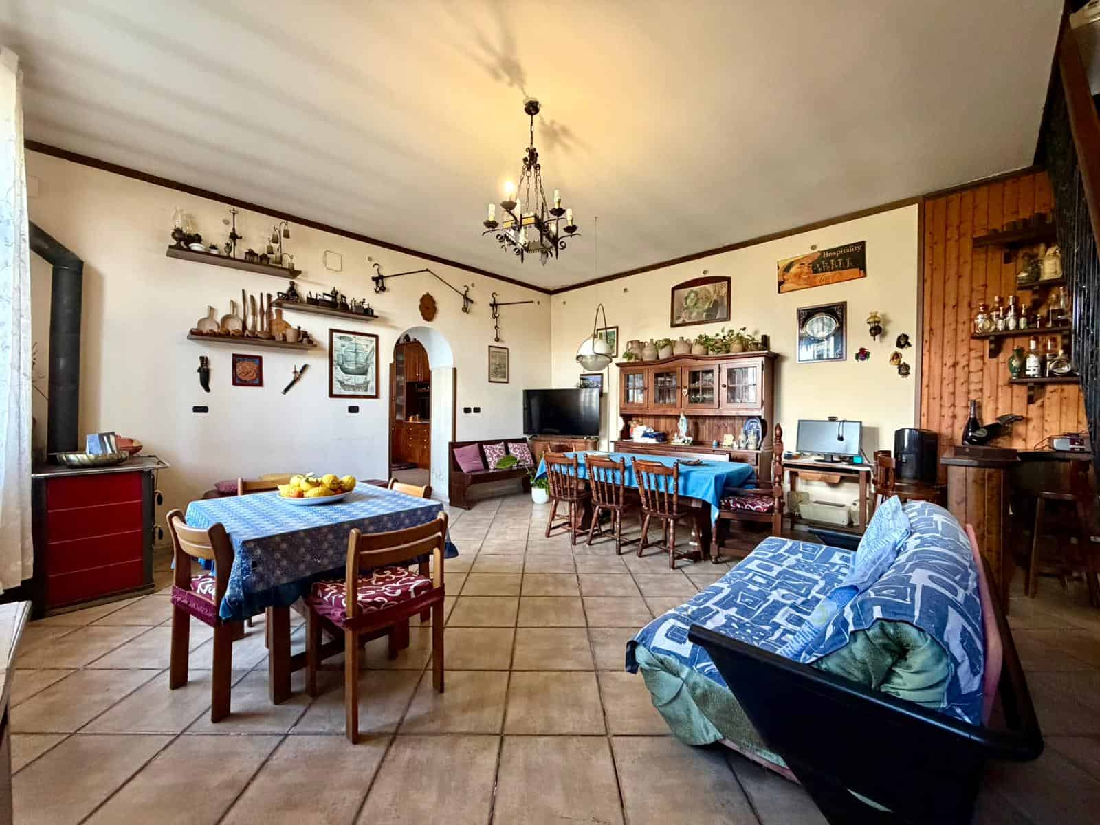 Interno di una casa accogliente con mobili in stile rustico, tavolo da pranzo, divano e decorazioni vintage, ambiente luminoso e spazioso.