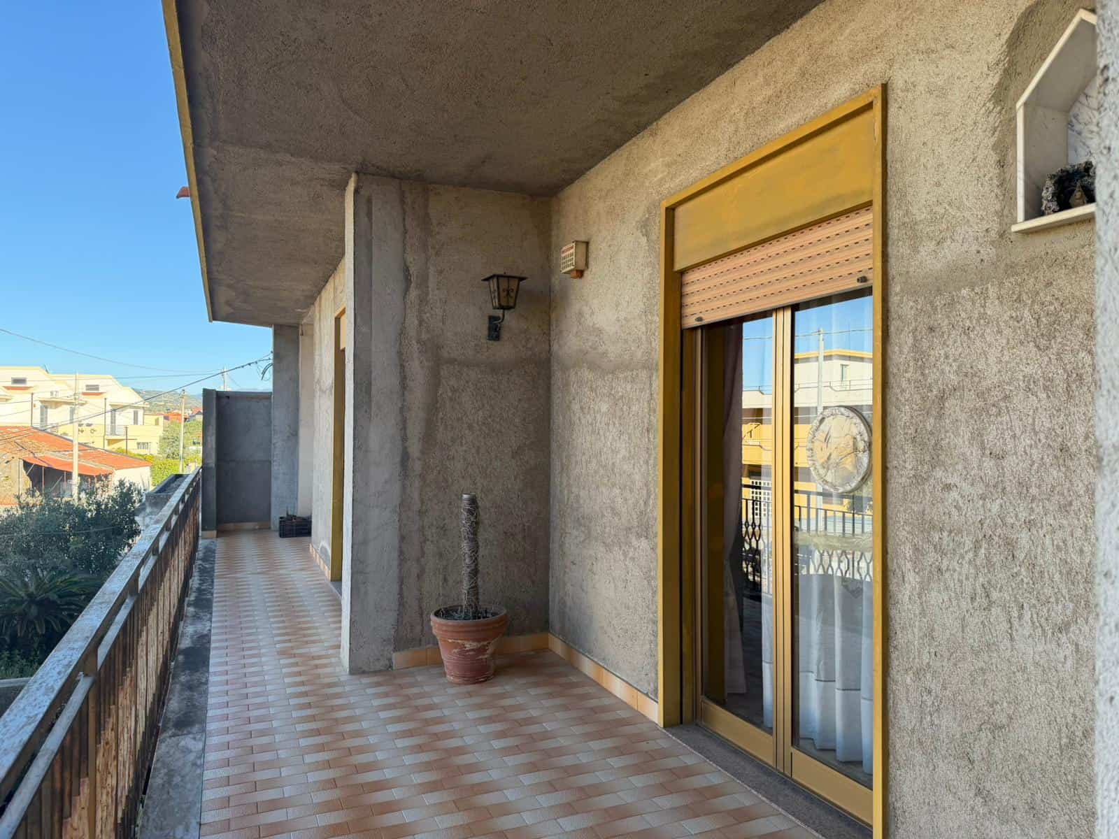 Ampia terrazza con vista panoramica, pavimentata con piastrelle in ceramica, ideale per relax e momenti all'aperto, con accesso a un appartamento in un edificio residenziale.