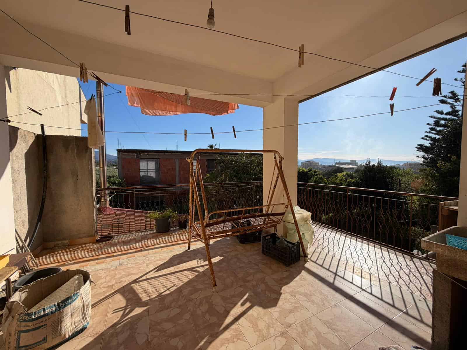 Lavatrice e stendibiancheria su un balcone soleggiato con vista panoramica, ideale per asciugare i panni all'aperto e godersi l'aria fresca. Perfetto per case in zona residenziale tranquilla.