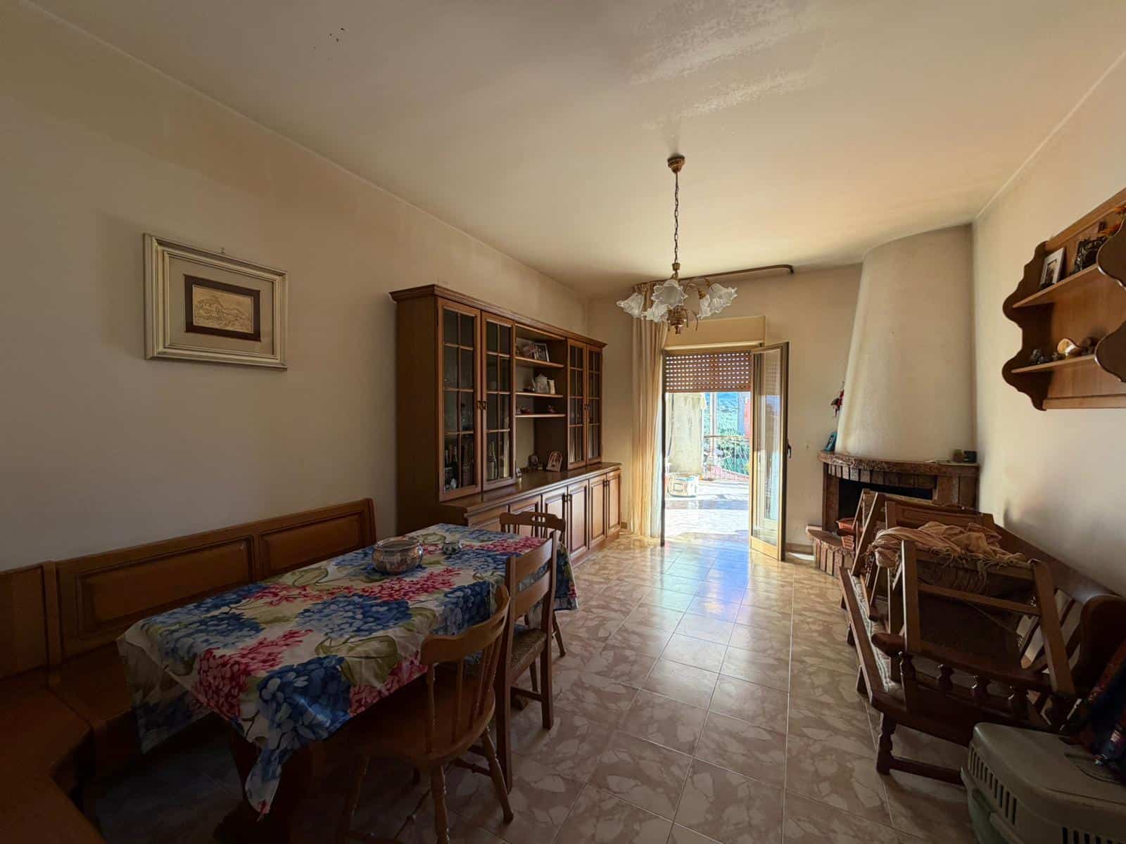 Una stanza soggiorno spaziosa e luminosa con mobili in legno, camino e accessori decorativi, ideale per vivere in comfort e stile. Perfetta per famiglie o coppie che cercano un'abitazione accogliente.