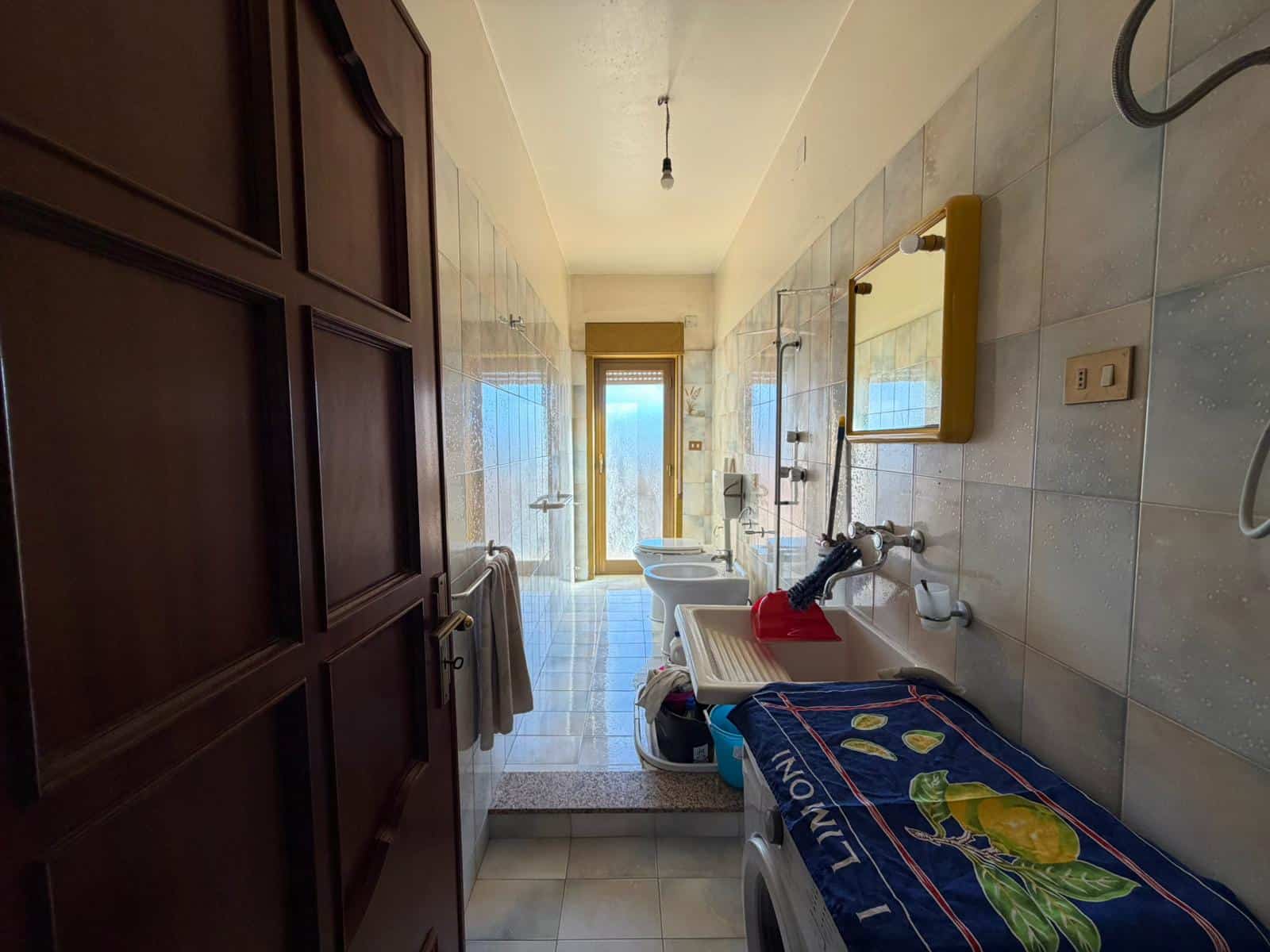 Lavanderia spaziosa con lavatrice, asciugatrice e lavabo, illuminata da luce naturale, ideale per la gestione quotidiana della casa.