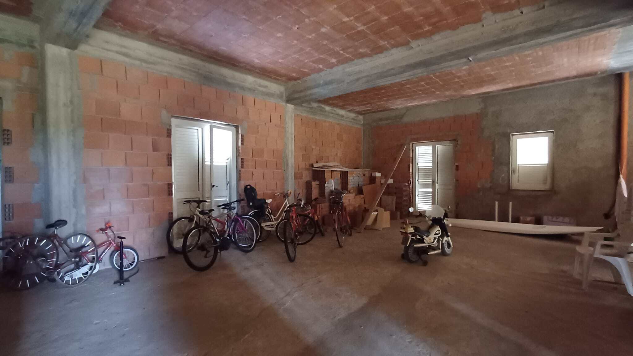Cameretta in fase di ristrutturazione con biciclette e attrezzi, spazio ampio e luminoso, ideale per progetti di rinnovamento e miglioramento abitativo.