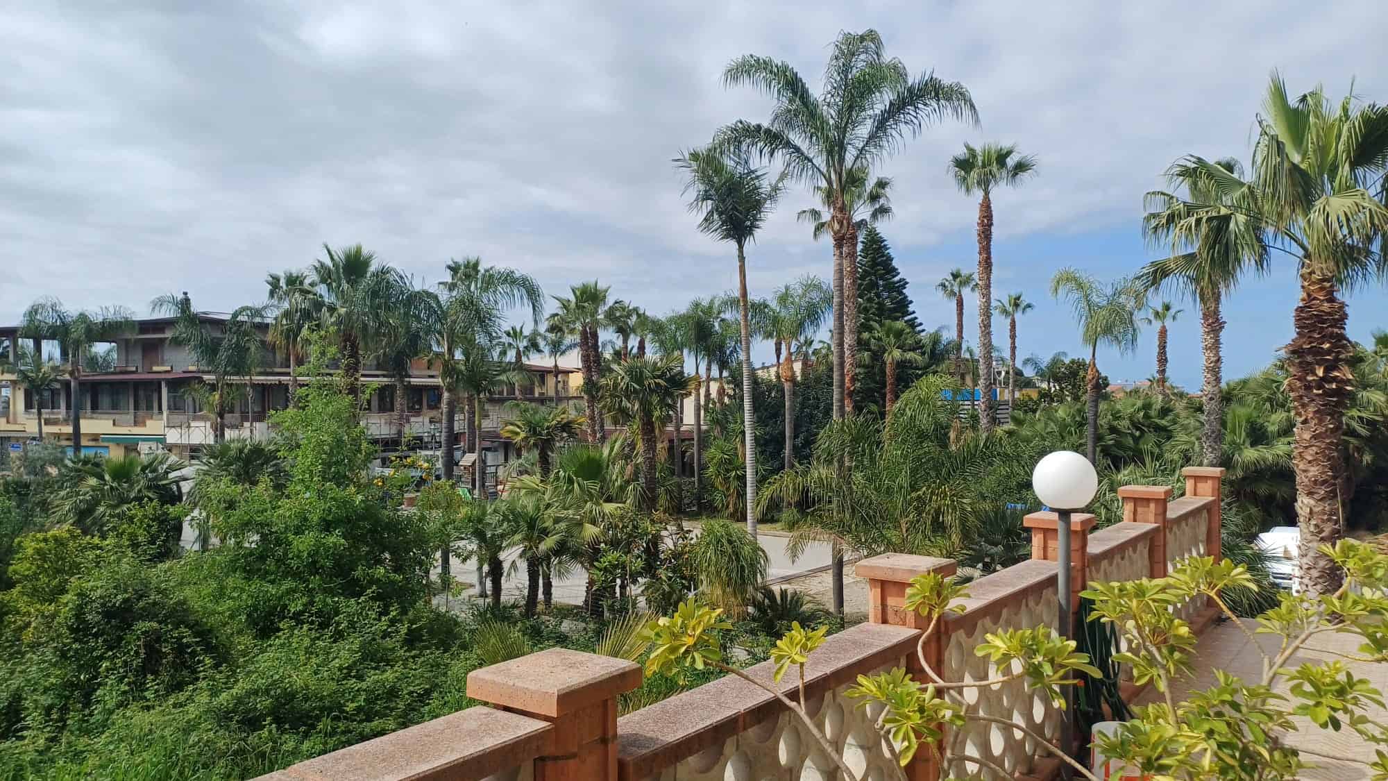 Ampia vista di un complesso residenziale con palme e vegetazione tropicale, ambienti moderni e ben curati, ideale per chi cerca case di lusso vicino alla natura in una zona esclusiva.