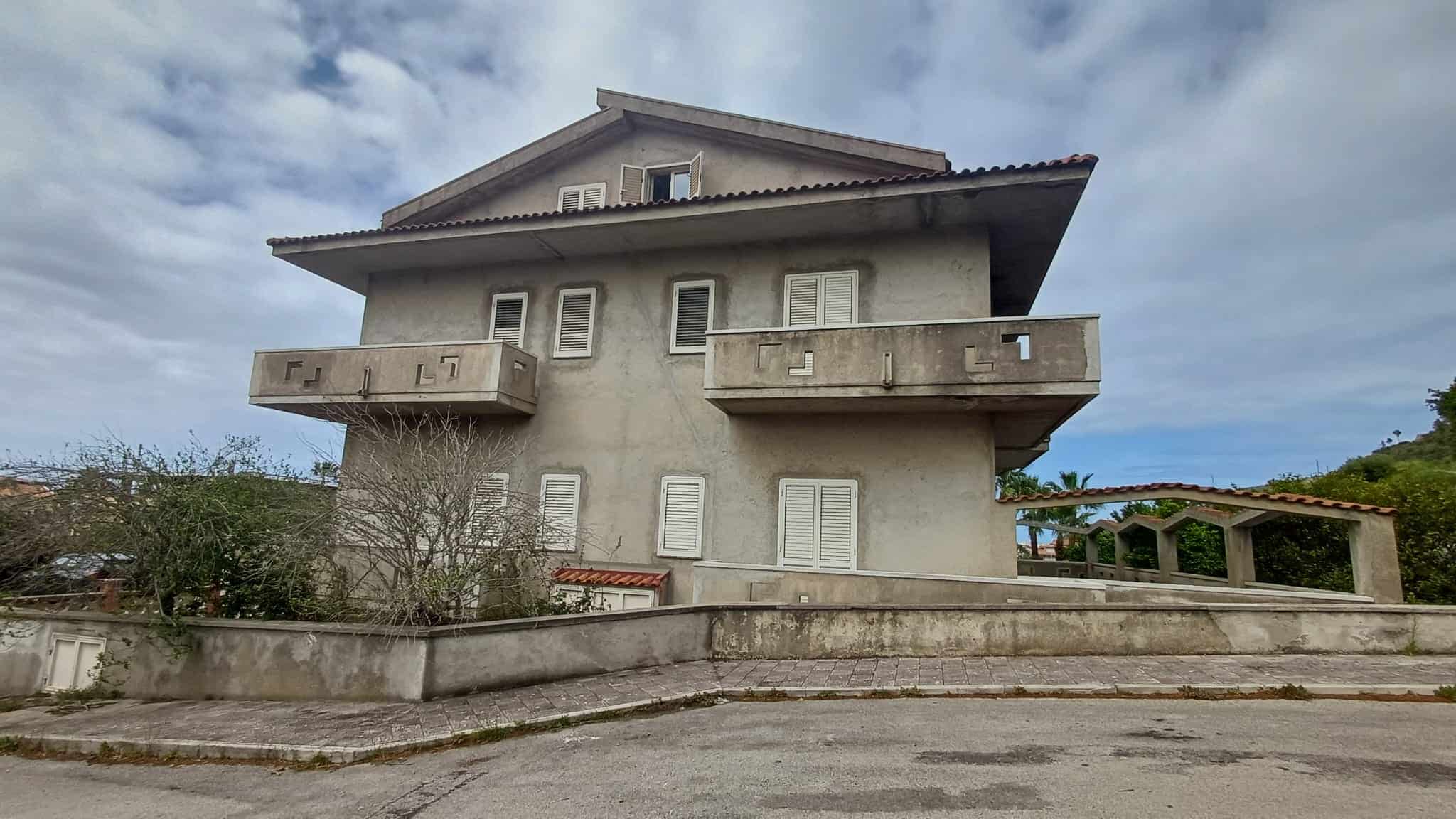 Balcone di un edificio residenziale con vista panoramica, struttura moderna e facciata in cemento, situato in un'area tranquilla e verdeggiante, ideale per investimenti immobiliari e affitti a breve t.