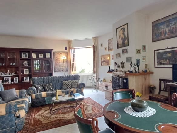 Elegante soggiorno con divani blu e arredi classici, decorato con quadri e oggetti d'arte, illuminato da luce naturale, ideale per vivere momenti di relax e convivialità.