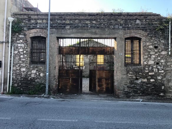 Anticamera in pietra con cancello in ferro battuto, ingresso storico di un edificio antico in stile rustico.