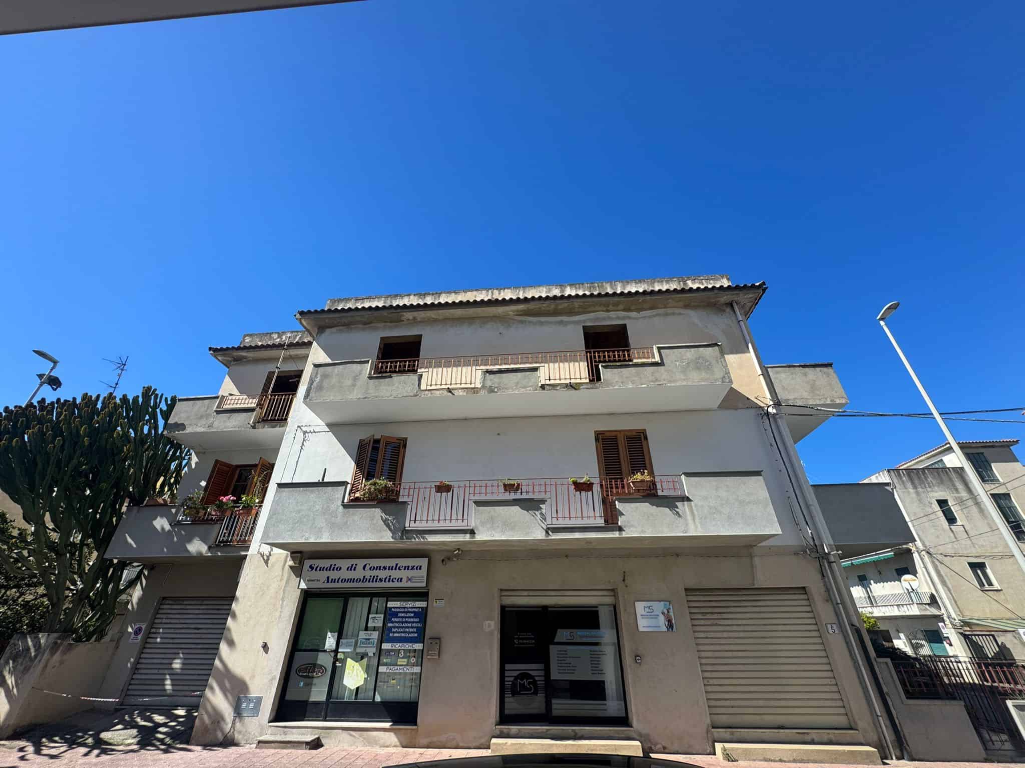 Vendita di immobili residenziali a Napoli, edificio multifamiliare con negozio al piano terra, facciata moderna e balconi, situato in zona urbana ben servita e facilmente accessibile.