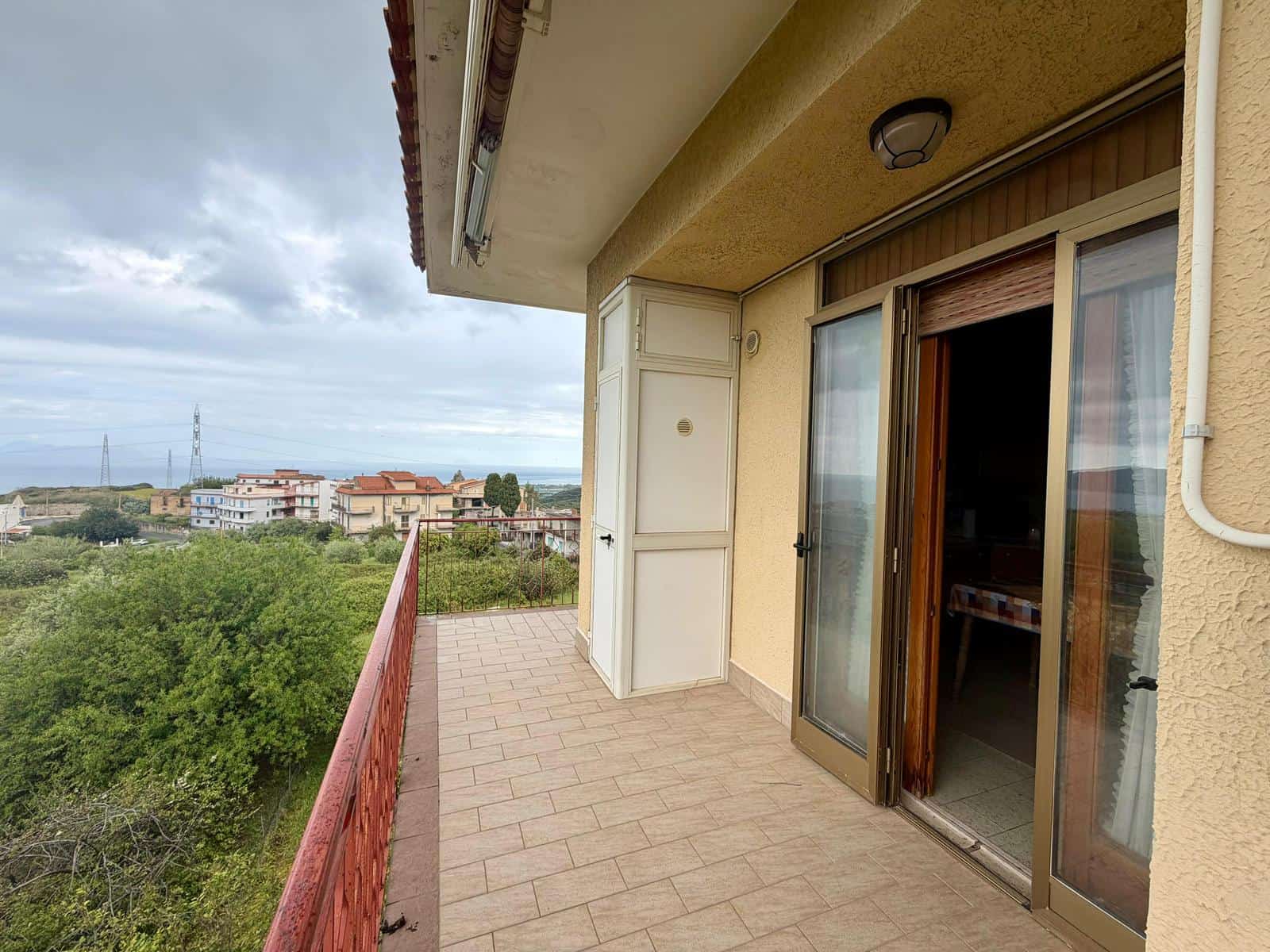 Balcone di un appartamento con vista panoramica sulla città e sulla natura circostante, ideale per momenti di relax all'aperto.