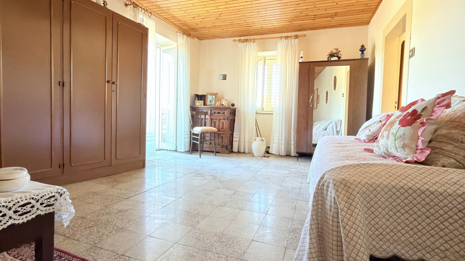 Ampia stanza soggiorno luminosa con mobili in legno, divano con cuscini decorativi e accessori eleganti, ideale per vivere momenti di relax e convivialità.
