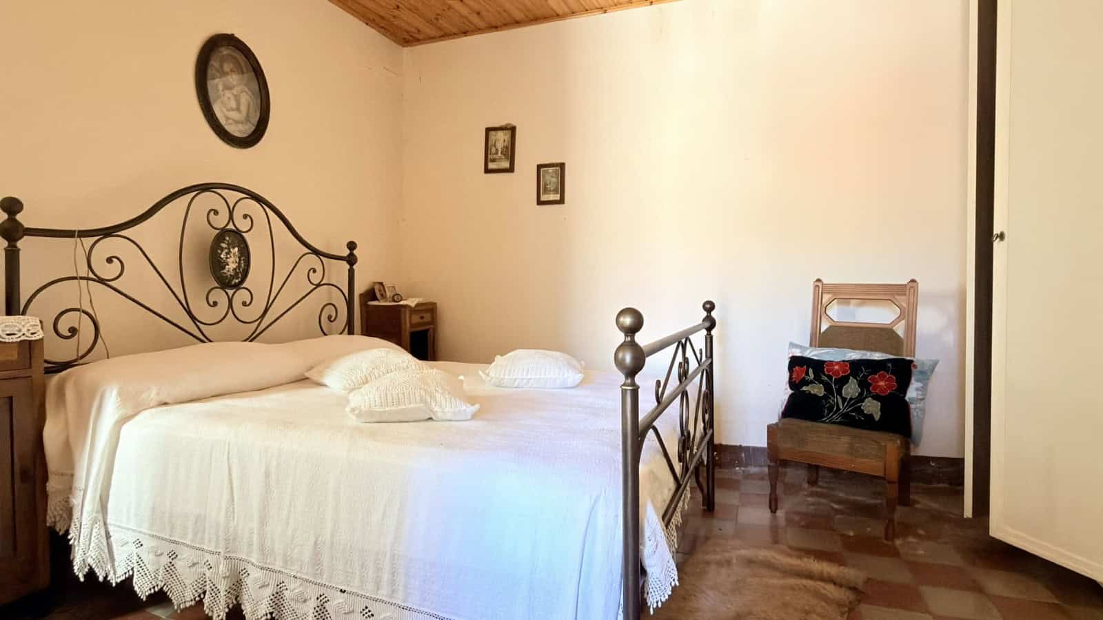 Letto matrimoniale con testiera in ferro battuto, camera da letto accogliente e luminosa con arredi classici e pareti decorate, ideale per ambienti di relax e comfort.