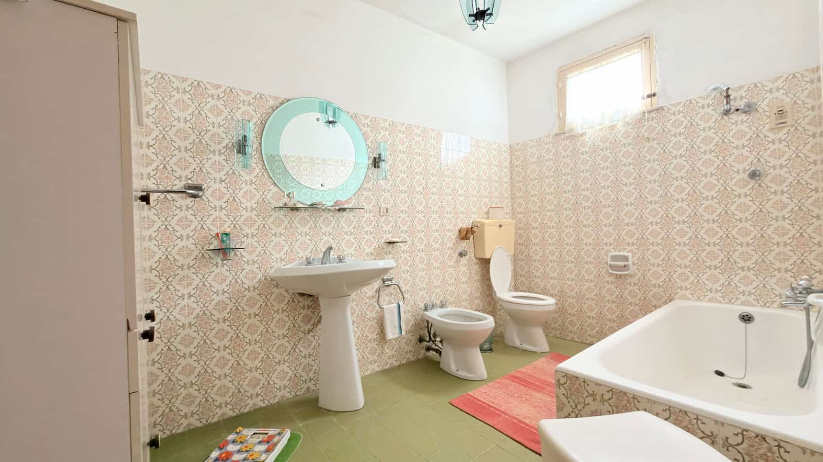Lavabo e bagno con piastrelle decorative, vasca da bagno e servizi igienici in un ambiente luminoso e spazioso. Ideale per case di charme o ristrutturazioni di interni eleganti.
