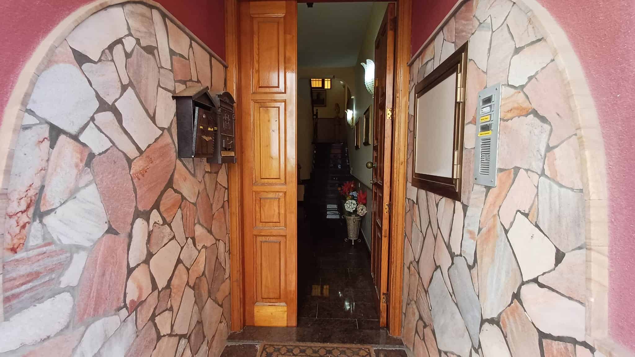 Porte d'ingresso in legno con pareti rivestite in pietra, ingresso di casa accogliente e rustica, dettagli di design per abitazioni in stile tradizionale italiano.