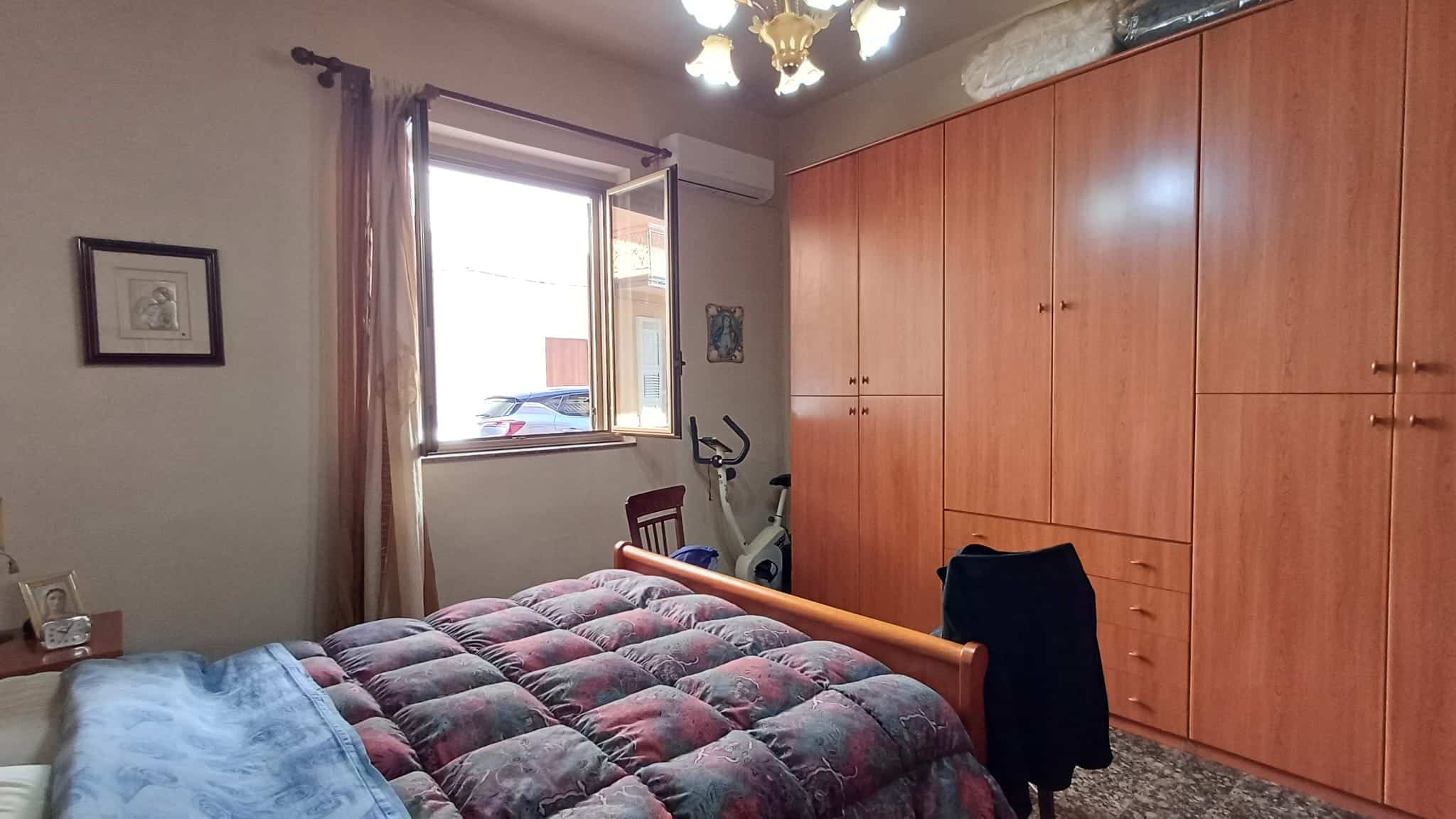 Letto matrimoniale con armadio a muro in una camera da letto luminosa e accogliente, con finestra che permette l'ingresso di luce naturale e arredi pratici.