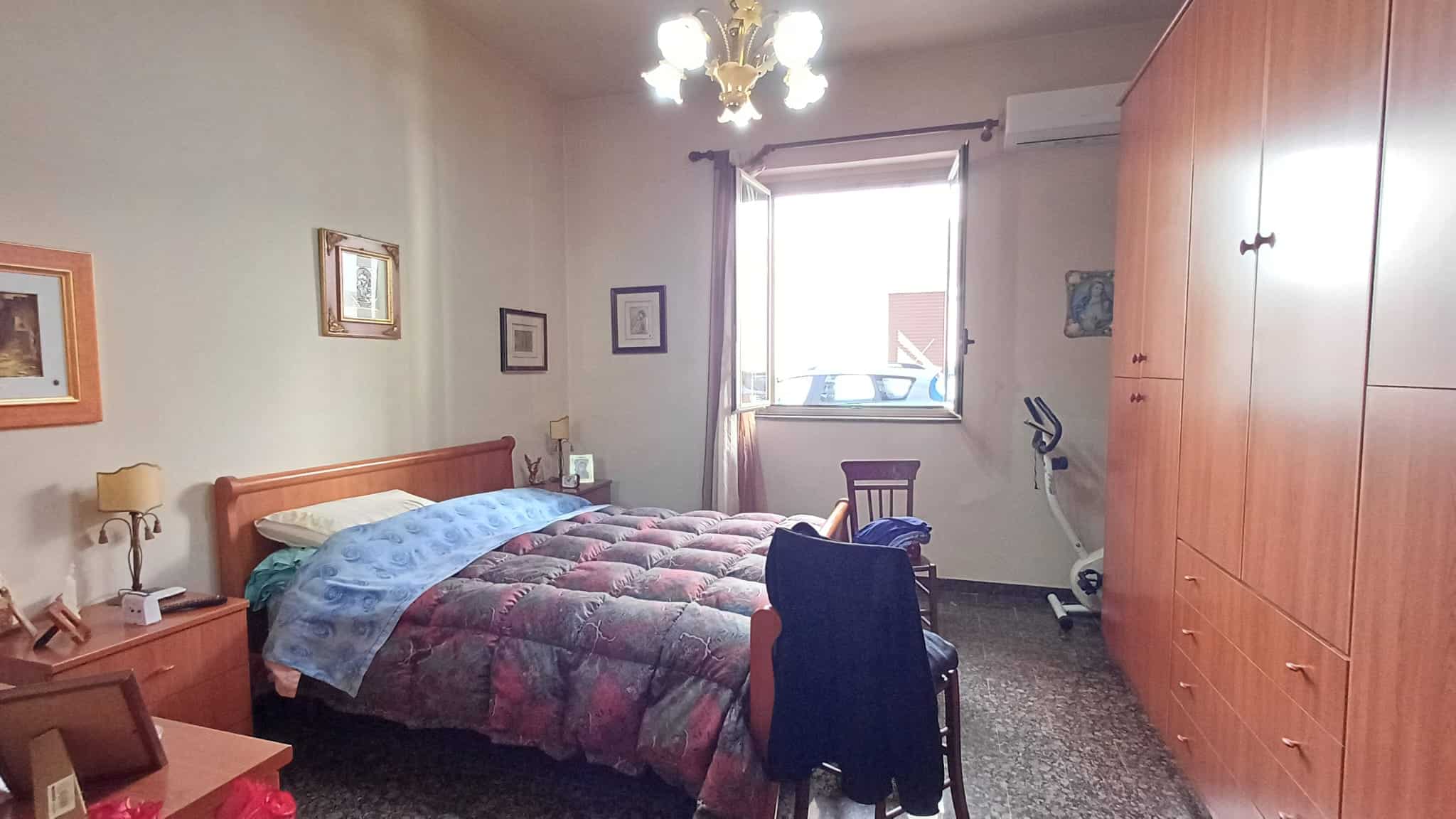 Letto matrimoniale in camera da letto con armadio a muro, scrivania e finestra luminosa, ideale per appartamenti in vendita o affitto a NextCasa.