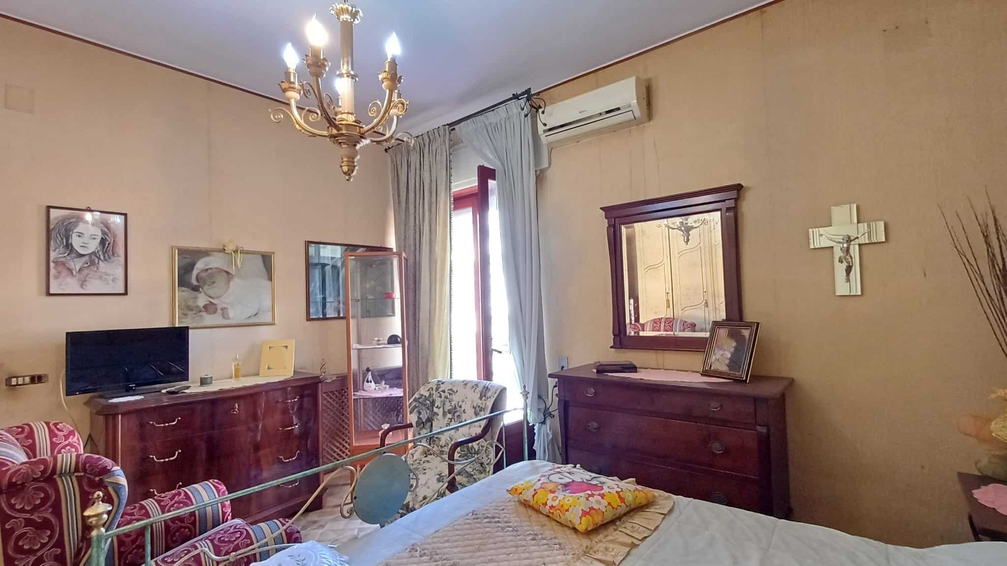 Elegante soggiorno con mobili classici, lampadario a chandelier, specchio, e decorazioni vintage, ideale per ambienti accoglienti e raffinati.