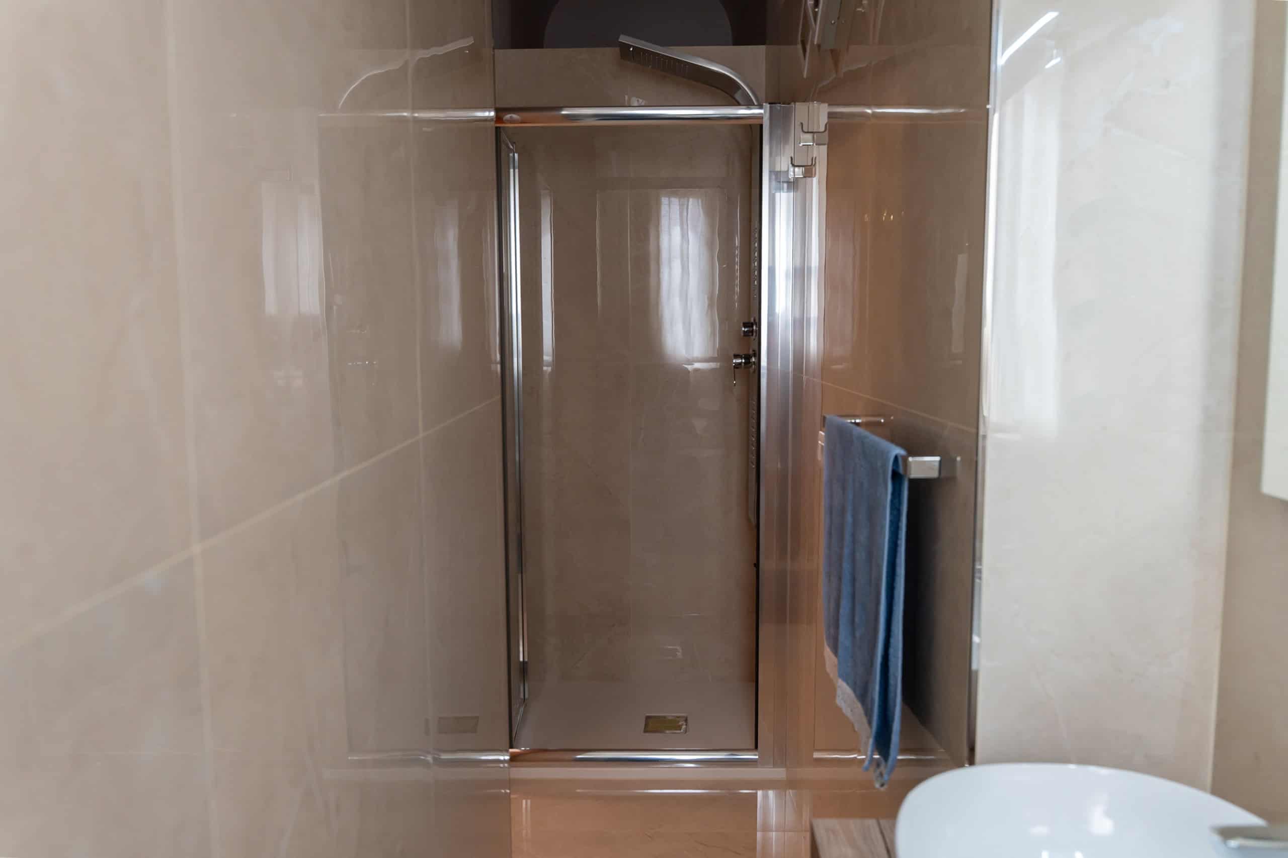 Lavabo e porta doccia in un bagno moderno con piastrelle beige, spazio funzionale e design pulito, ideale per case di alta qualità.