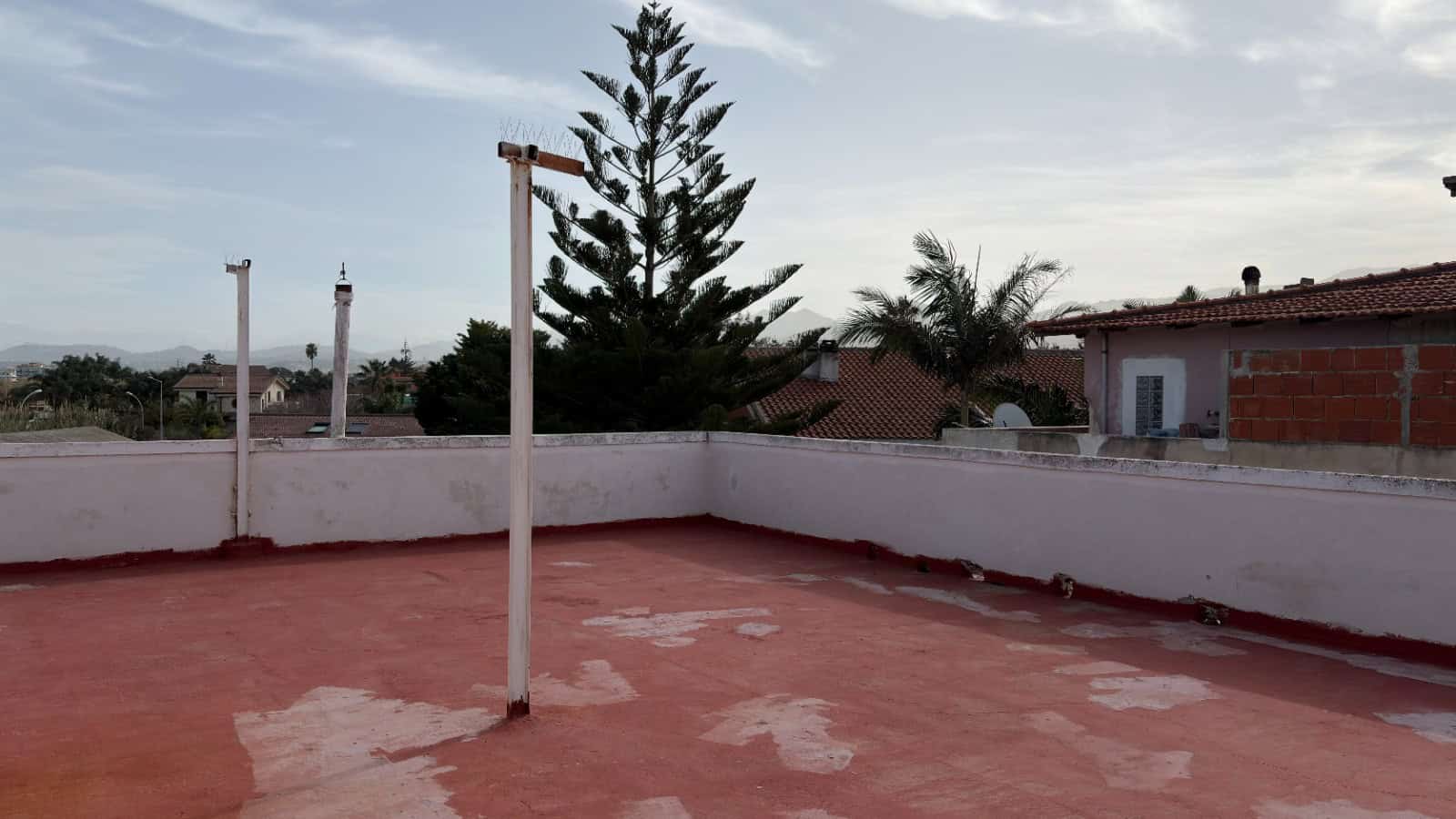 Lavatrice all'aperto su terrazza con vista su alberi e case, ideale per stendere i panni all'aperto in un ambiente residenziale soleggiato e tranquillo.