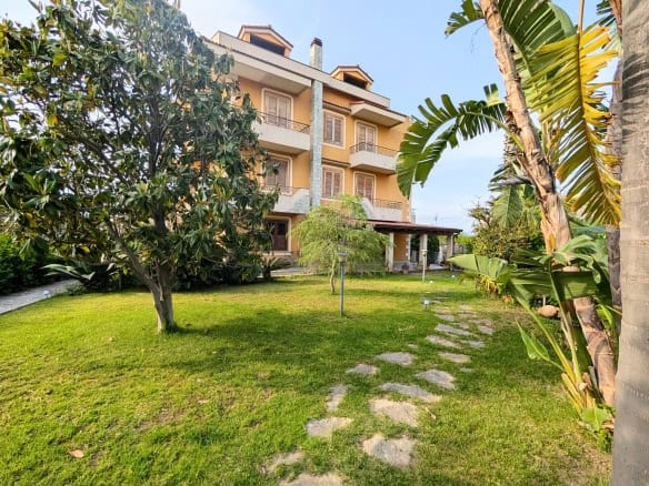 Piante tropicali e giardino ben curato davanti a un edificio residenziale con balconi e terrazze, ambiente tranquillo e verdeggiante.