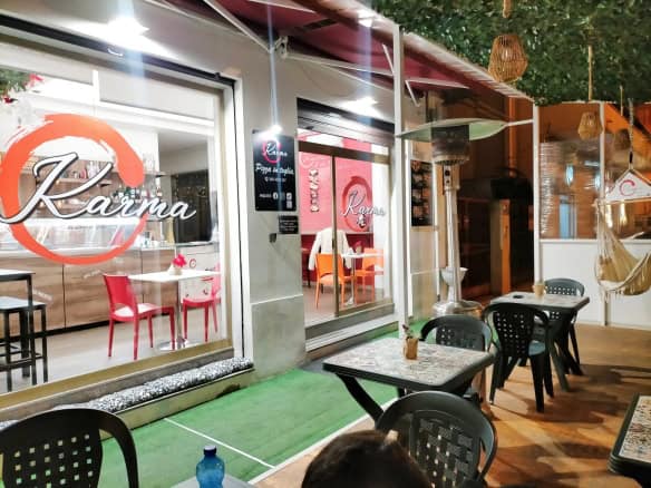 Il logo di NextCasa su una vetrina di un locale con tavoli all'aperto, atmosfera accogliente e moderna, illuminazione calda e arredi eleganti, ideale per ristoranti o caffè in centro città.
