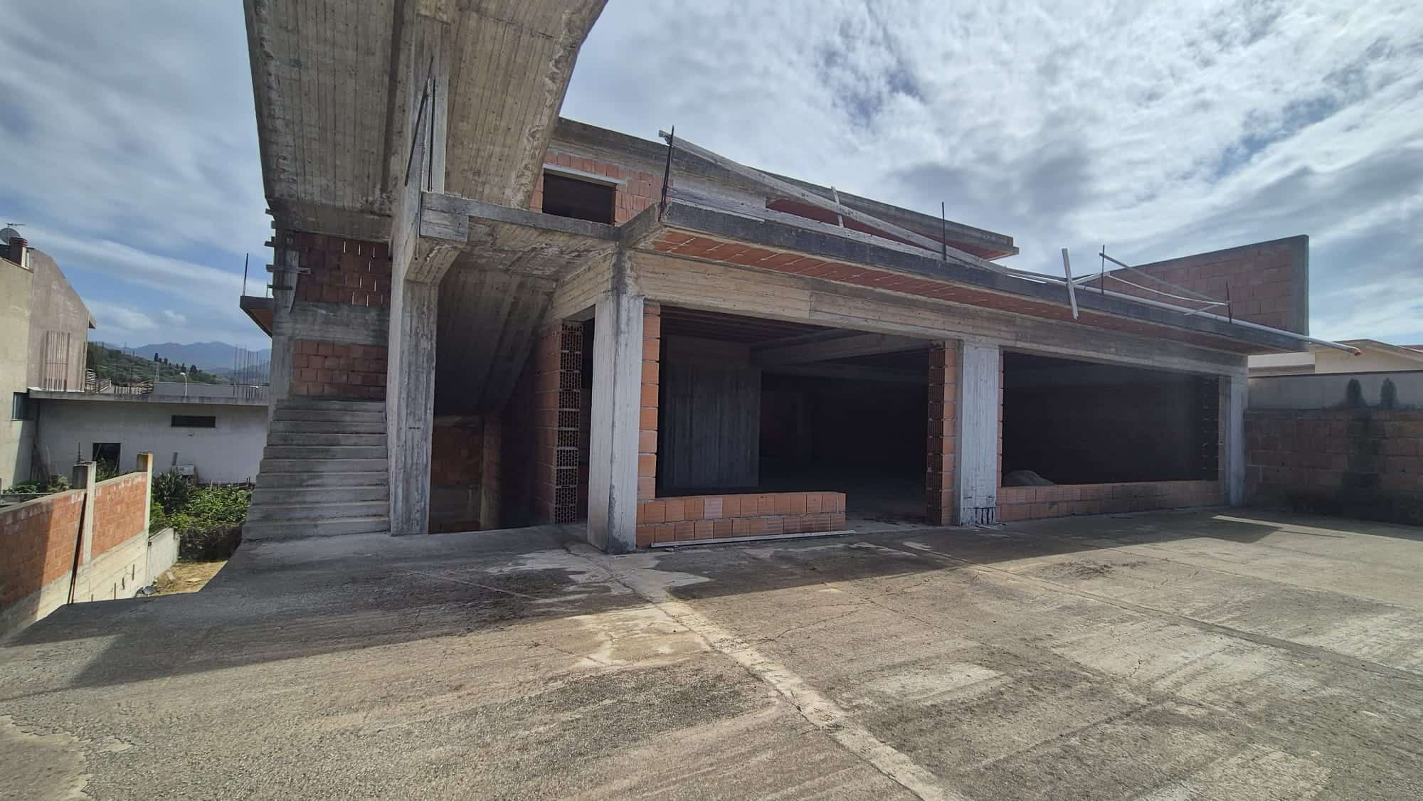Pannello di costruzione di una casa in cemento armato in fase di sviluppo, con struttura portante visibile e spazio per le future finiture e ambienti interni.