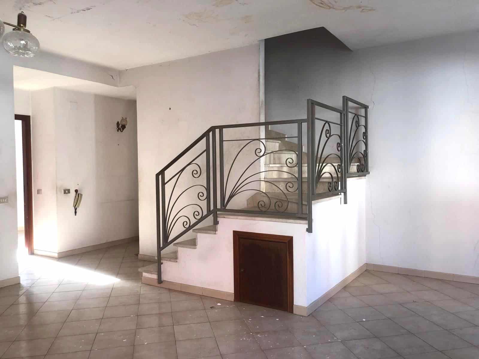 Scala interna in metallo con ringhiera decorativa in un appartamento vuoto, ideale per ristrutturazione e design moderno.