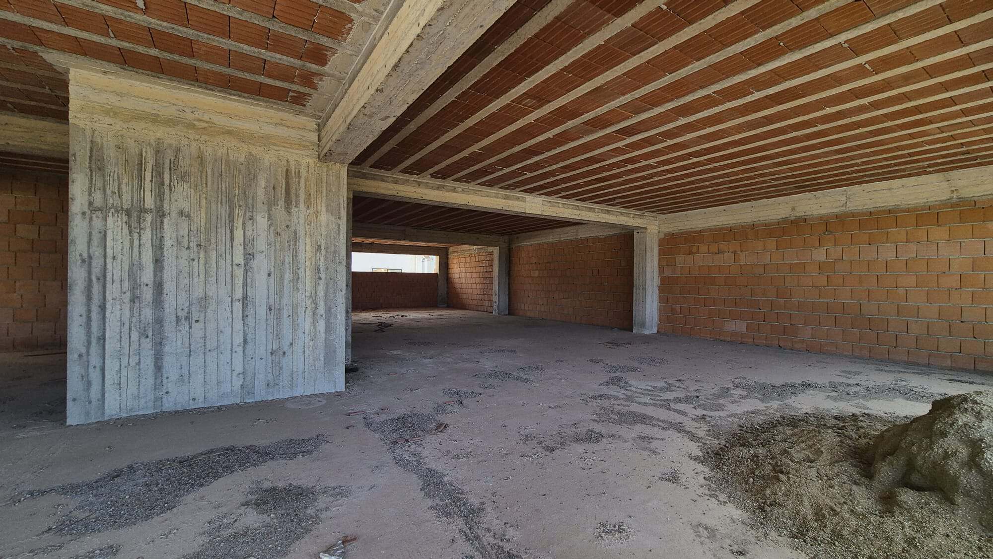 Porte aperte di un edificio in costruzione con struttura in cemento e mattoni, pronto per essere completato come spazio residenziale o commerciale.