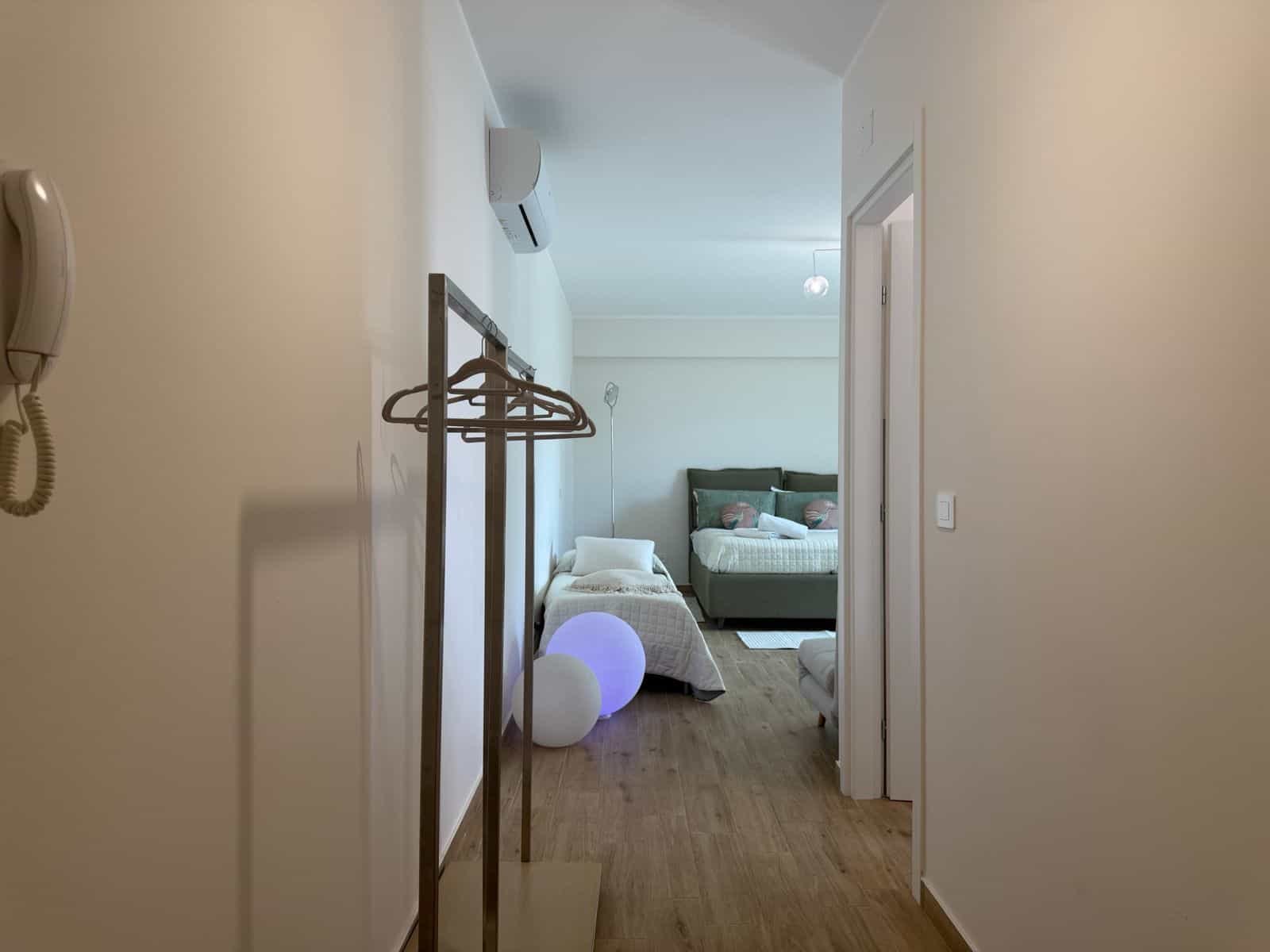 Camera che mostra un soggiorno moderno e luminoso con letto, armadio e decorazioni minimaliste in un appartamento in stile contemporaneo.