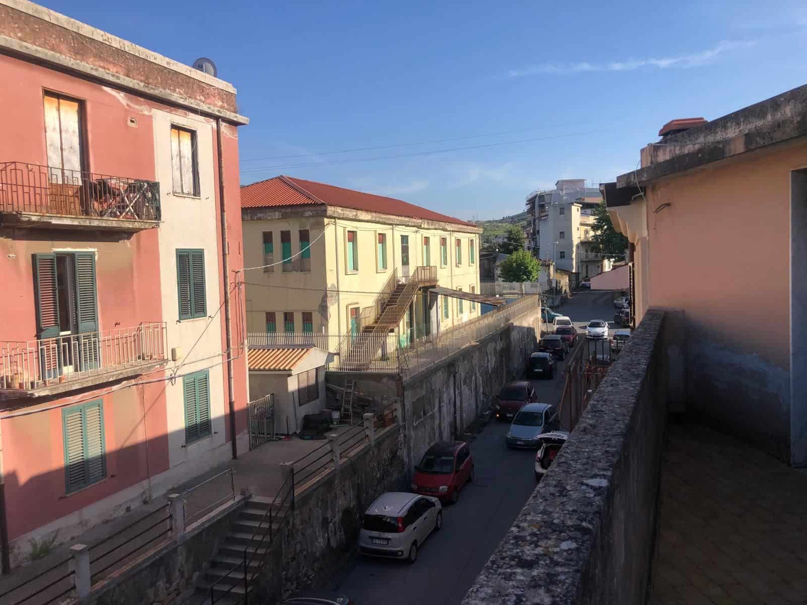 Vasta veduta di un quartiere residenziale con edifici colorati e strada trafficata, sotto un cielo sereno, rappresentando un ambiente urbano vivace e pittoresco in Italia.