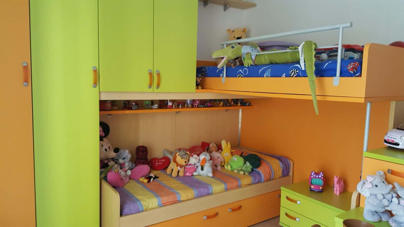 Letto a castello con armadio e giochi per bambini, ambiente colorato e accogliente.