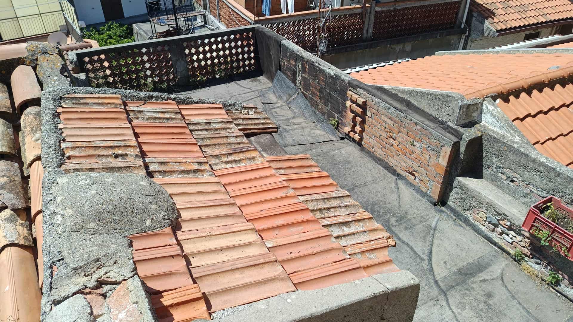 Tetto in tegole di terracotta su edificio residenziale, vista dall'alto con dettagli delle coperture e delle strutture di supporto.