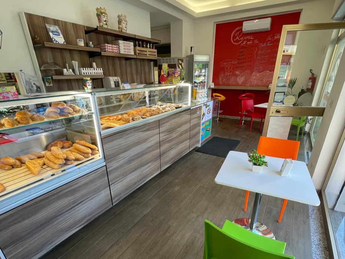Pane di pasticceria e dolciumi in vetrina in una caffetteria moderna con arredi colorati e atmosfera accogliente, ideale per colazioni e snack dolci.