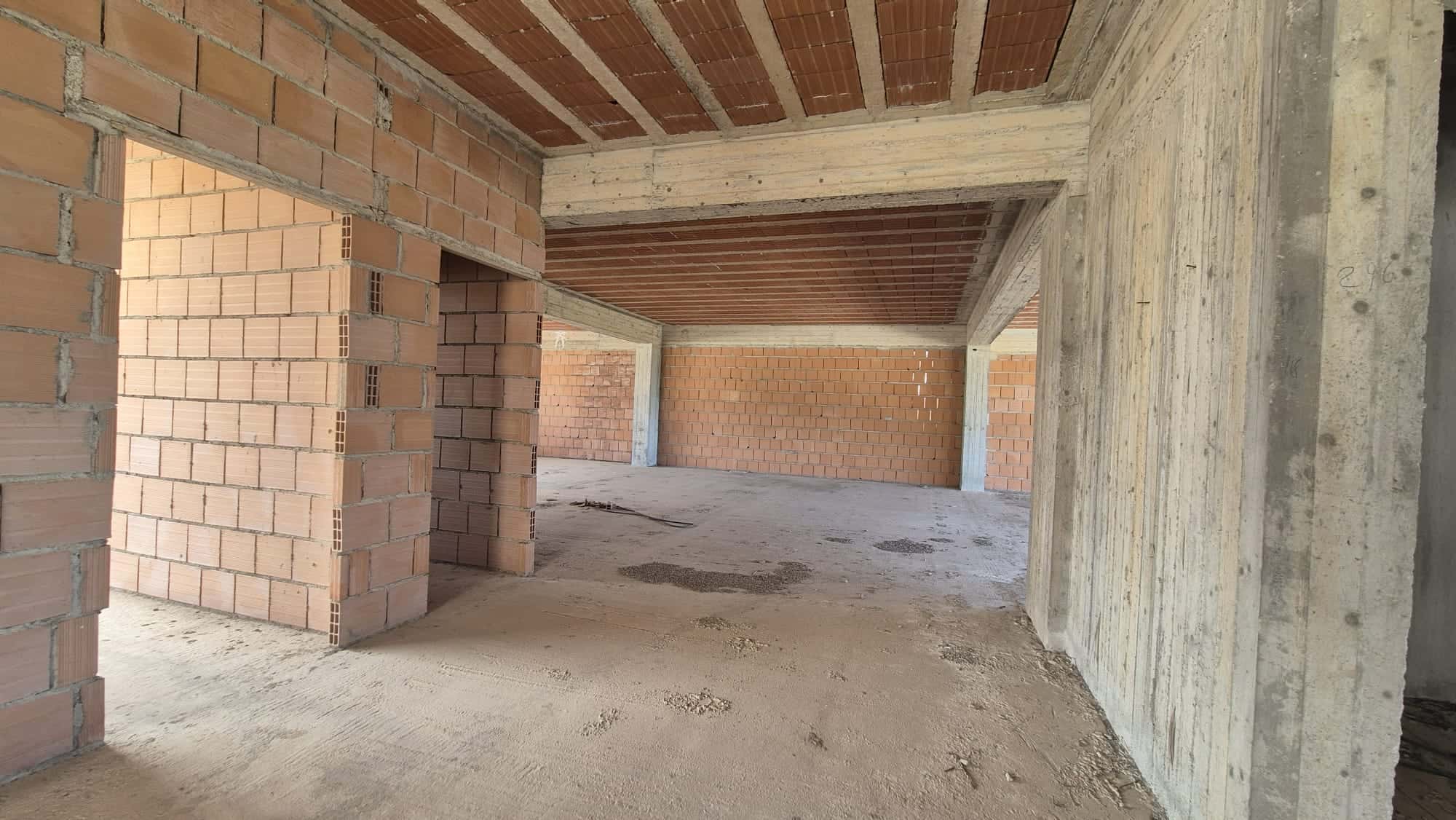 Cantiere edile con strutture in cemento e mattoni, pronto per la costruzione di un edificio residenziale o commerciale. L'ambiente è ancora in fase di costruzione, con pareti e soffitti non finiti.
