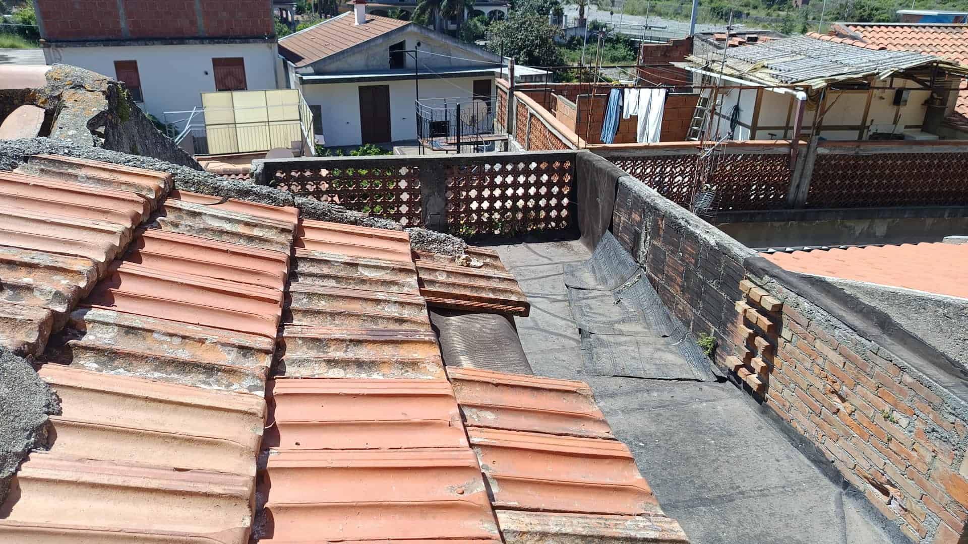 Tegola di copertura in terracotta rossa su tetto di un edificio residenziale, vista dall'alto.