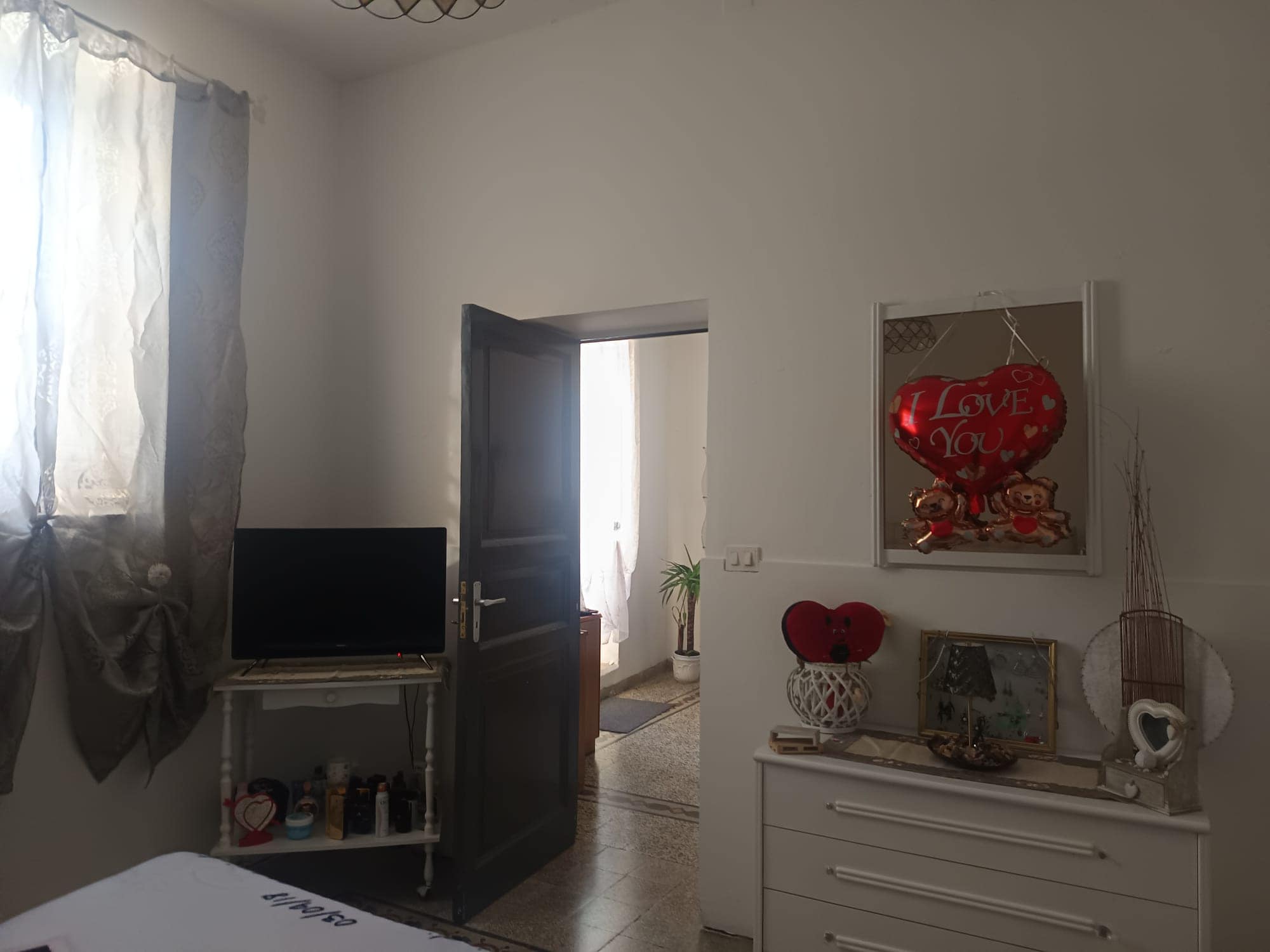 Porte aperta che conduce a una stanza luminosa con decorazioni romantiche e oggetti d'arredo eleganti, ideale per ambienti di casa accoglienti e raffinati.