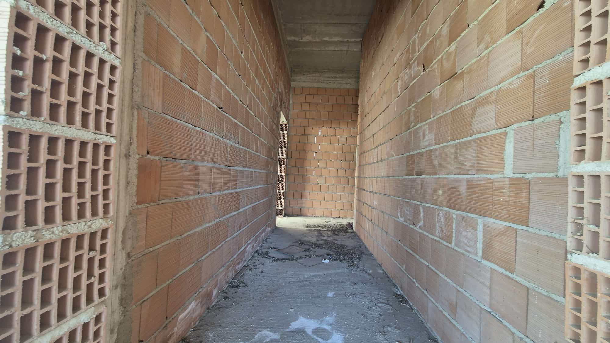 Cancello di un edificio in costruzione con pareti in mattoni a vista, pronto per essere completato.
