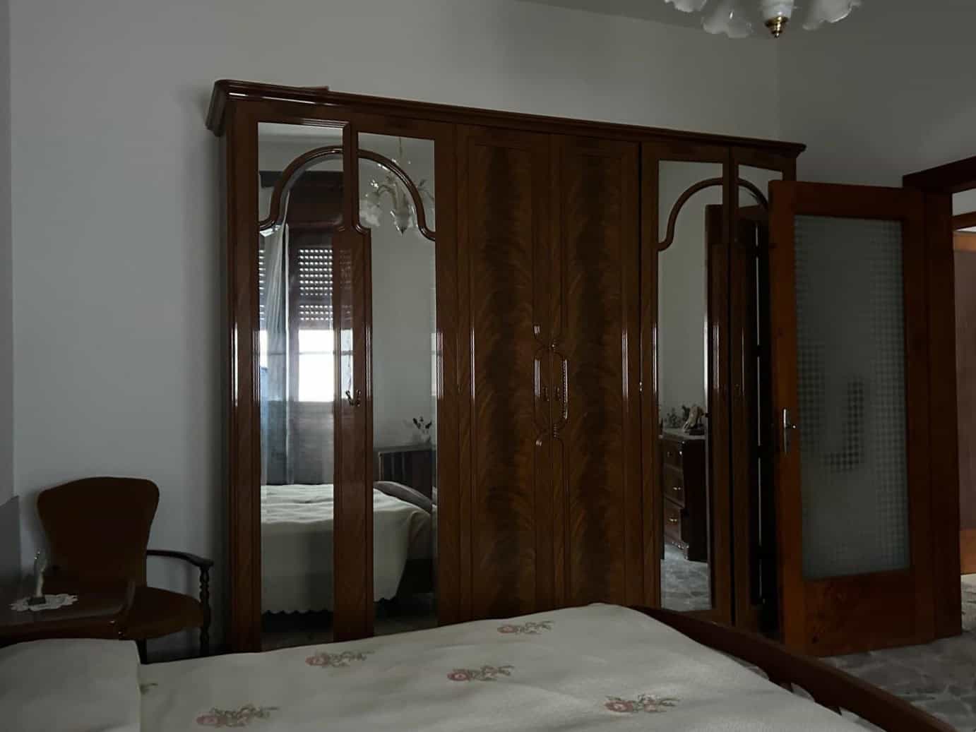 Armadio in legno con specchi e porta scorrevole in una camera da letto classica, arredamento elegante e funzionale.