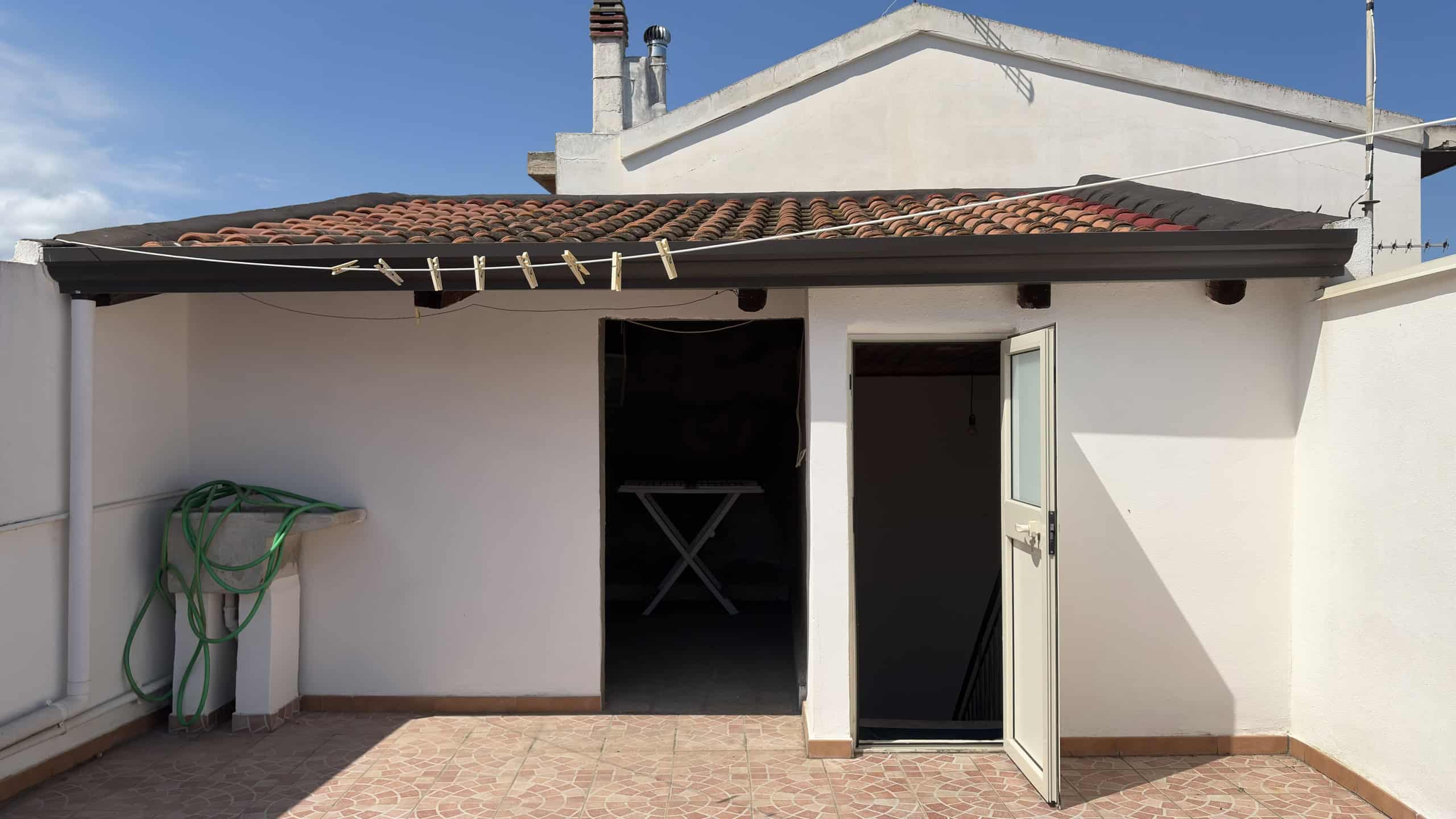 Ampio terrazzo esterno con pareti bianche e accesso tramite porta e finestra, ideale per relax e attività all'aperto.