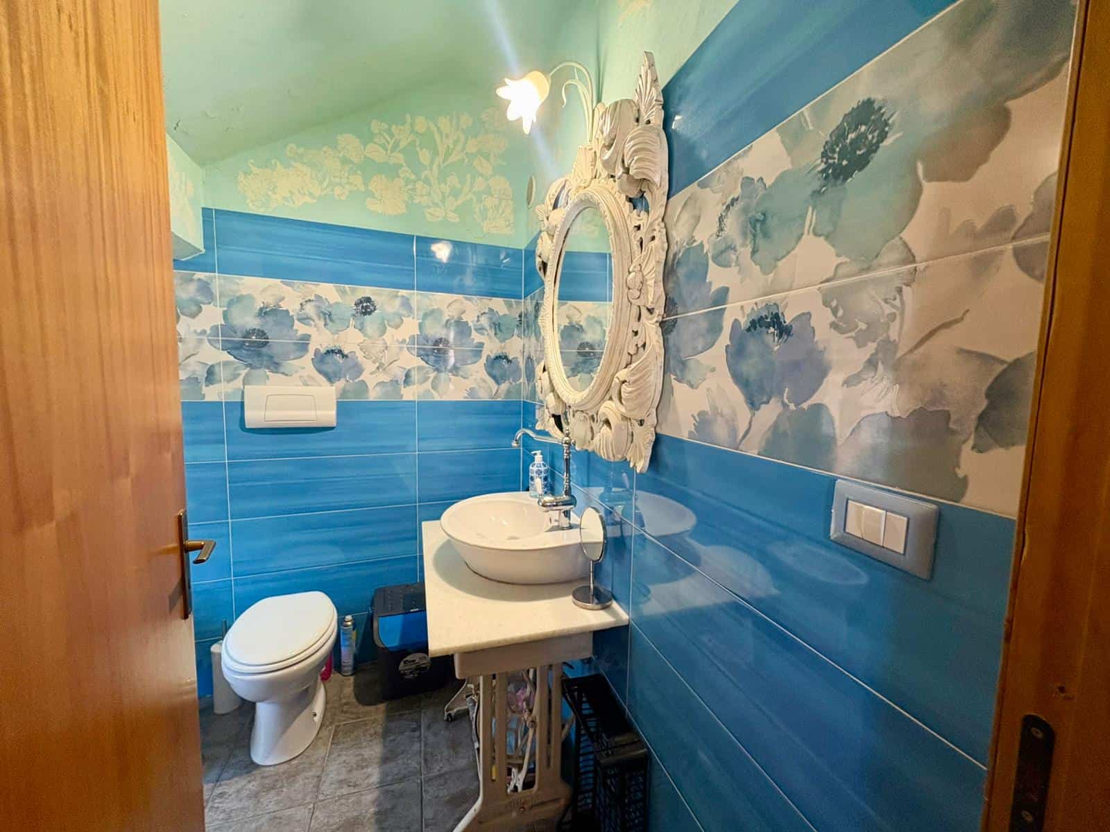 Lavabo e WC in un bagno moderno con pareti decorate a nuvole blu e dettagli eleganti, ideale per ambienti di comfort e stile.