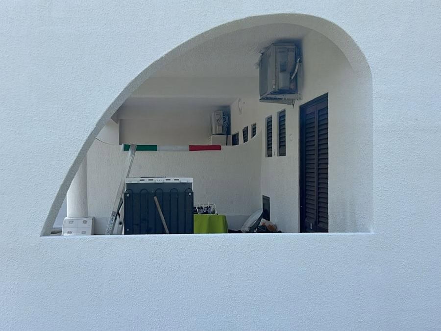 Lavanderia esterna con arredi e attrezzature per il bucato, coperta da un arco bianco, ideale per spazi all'aperto funzionali e pratici.
