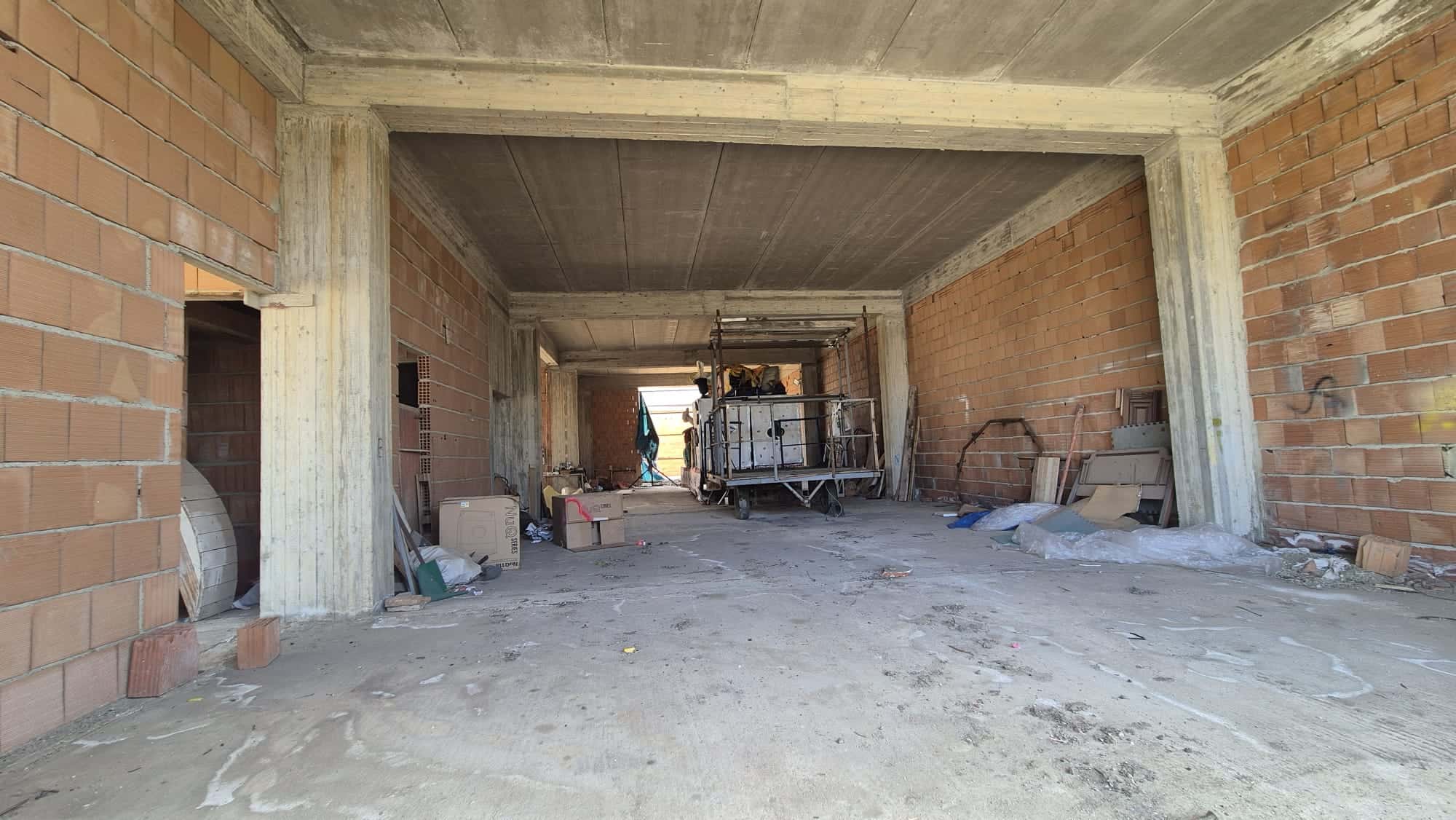 Cantiere edile con struttura in cemento e mattoni, pronto per la costruzione di un edificio residenziale o commerciale, con attrezzature e materiali da costruzione presenti sul sito.